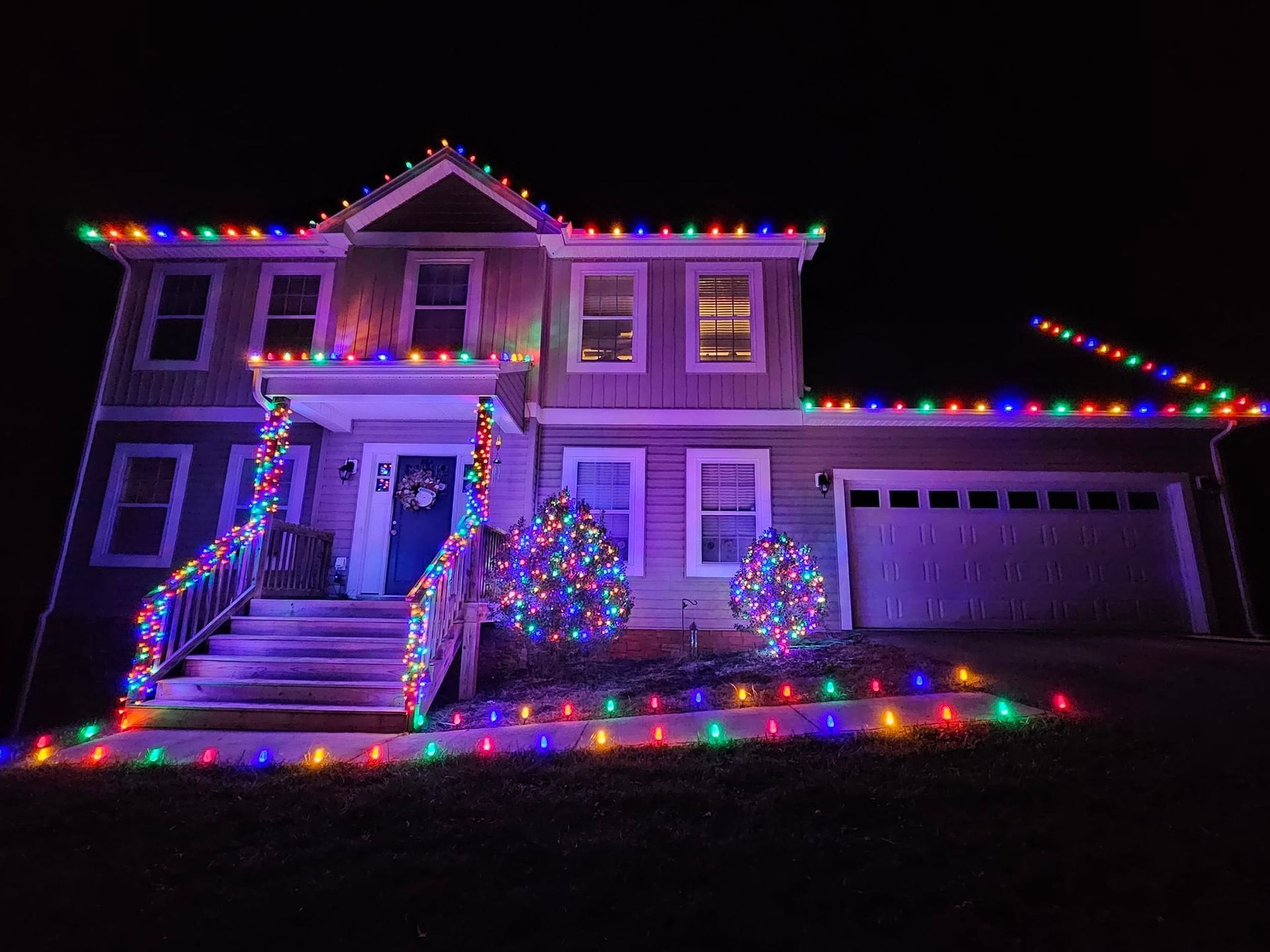 House decorated with colorful Christmas lights at night.