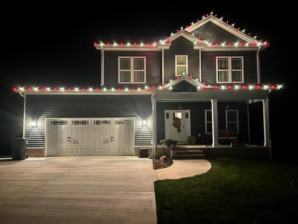 Two-story house at night with red and white Christmas lights outlining the roof.