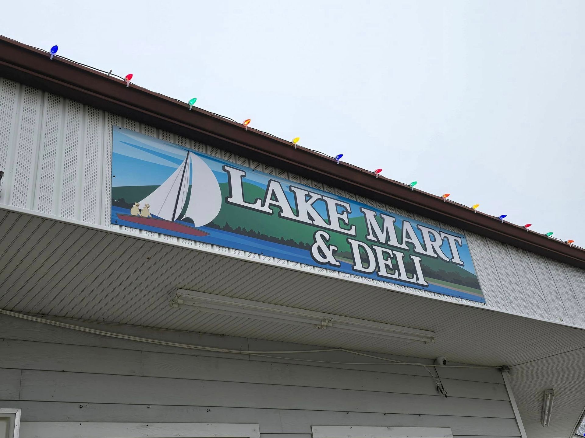 Sign for Lake Mart & Deli, featuring a sailboat image; exterior shot.