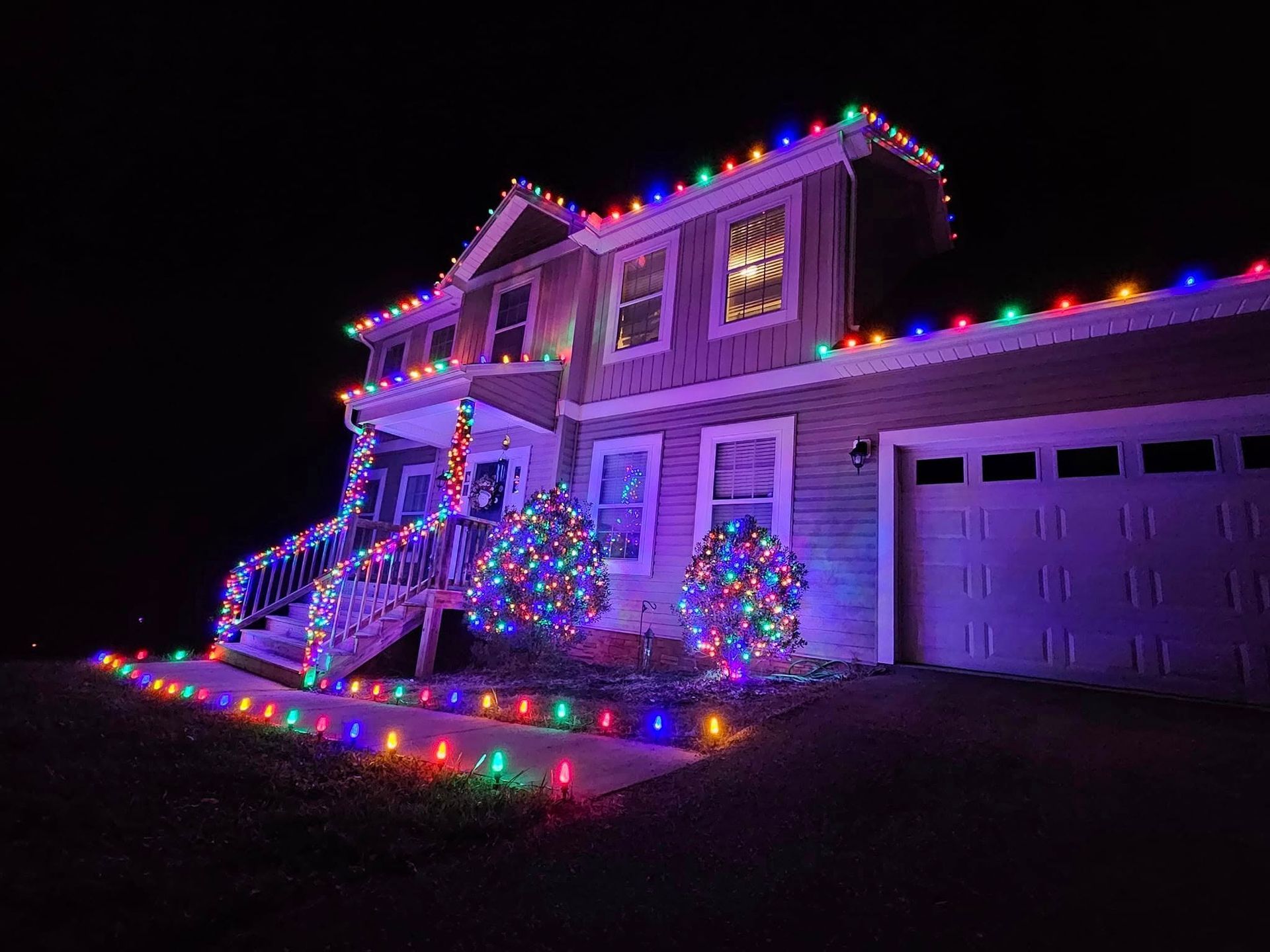 House decorated with colorful Christmas lights at night.