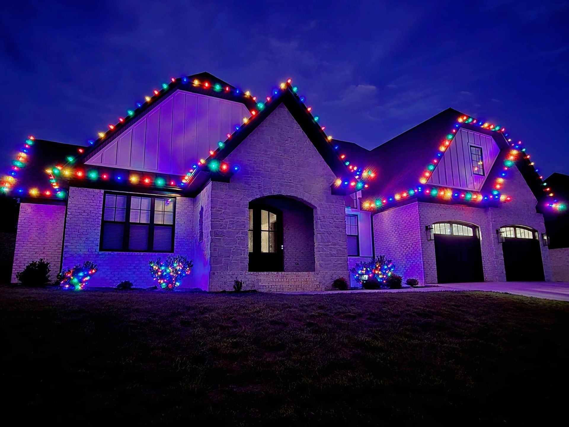 House decorated with colorful Christmas lights against a twilight sky.