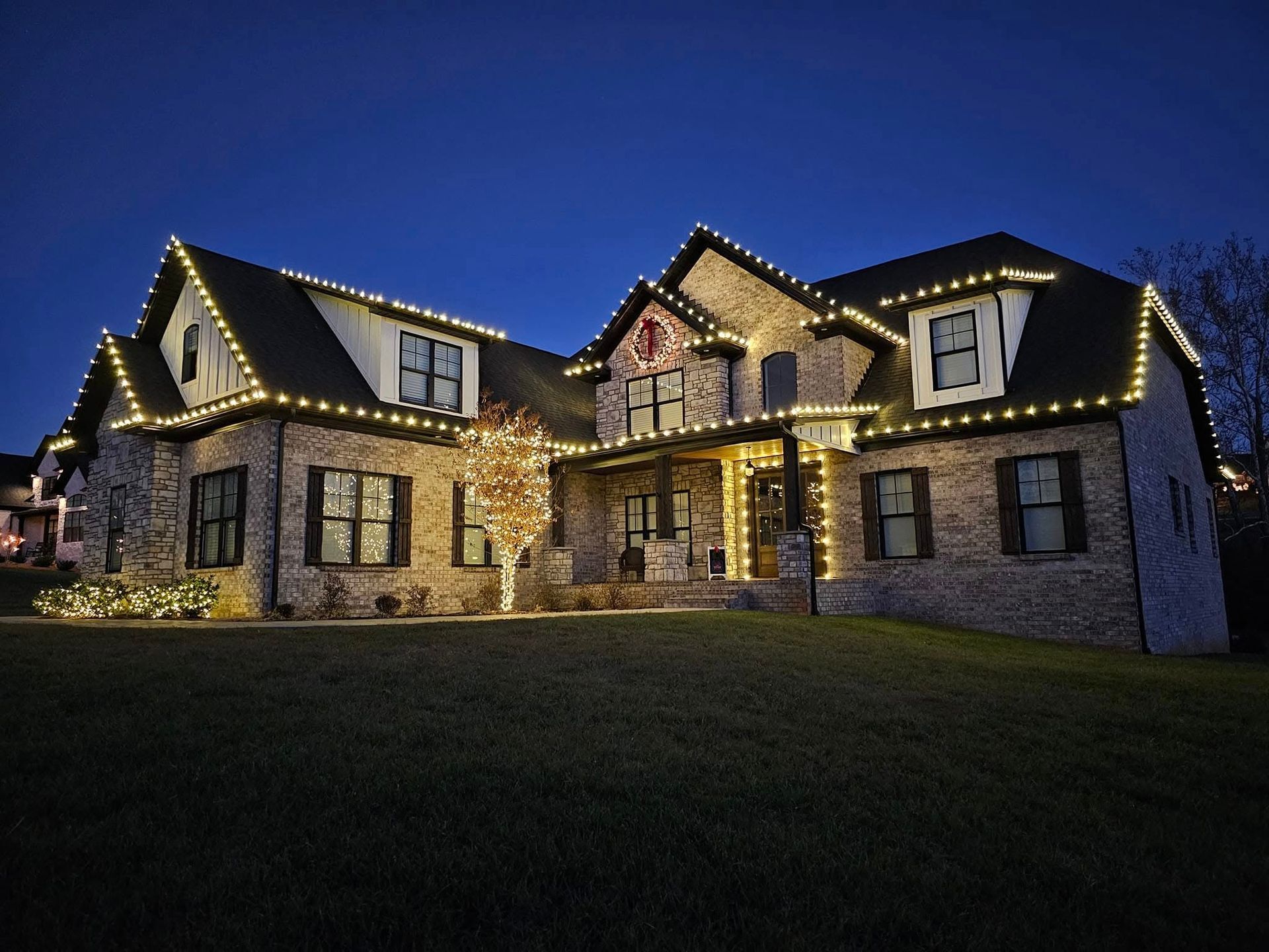House decorated with white Christmas lights against a dark blue sky.