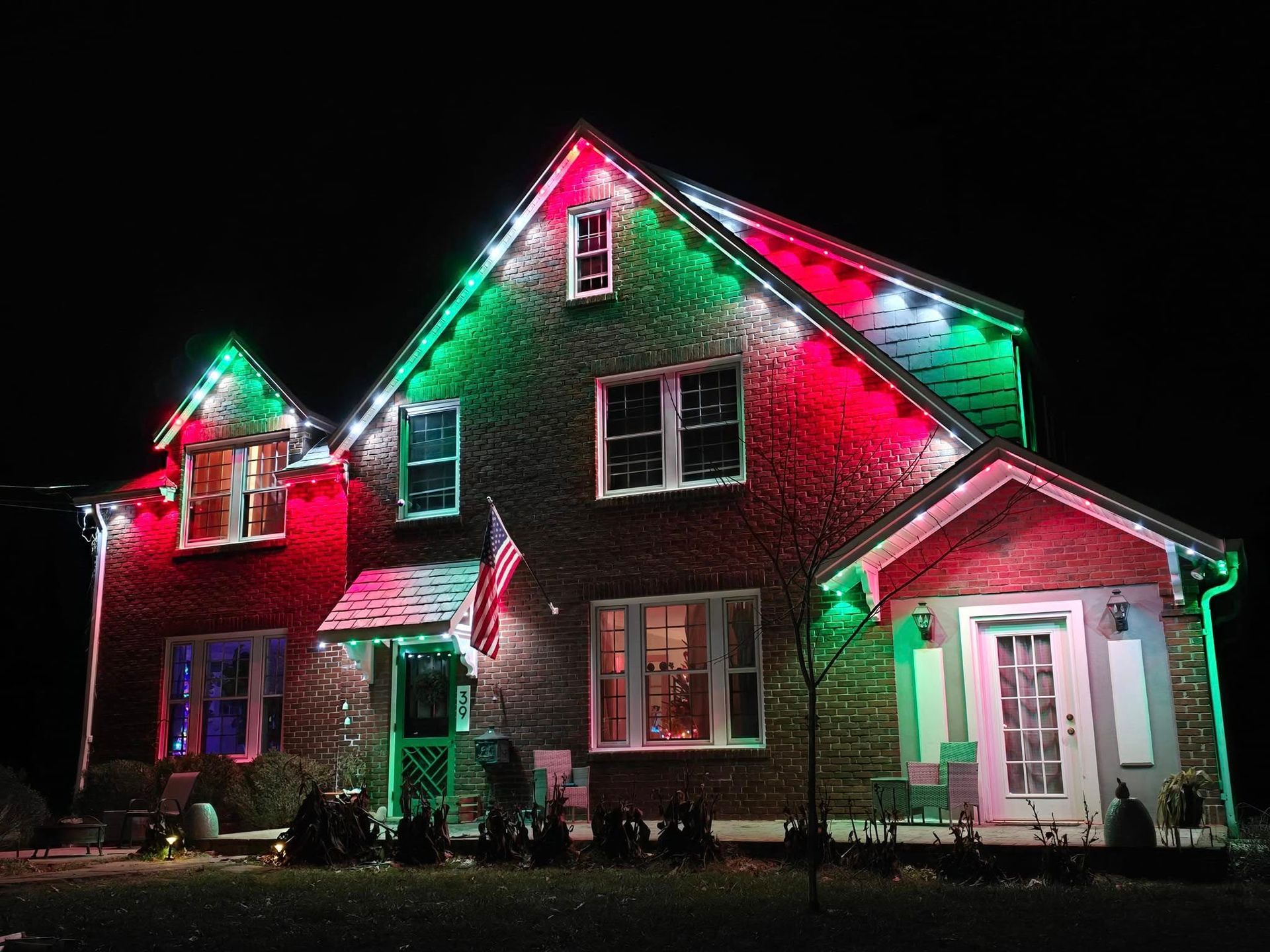 House decorated with Christmas lights, red and green, against a dark night sky.