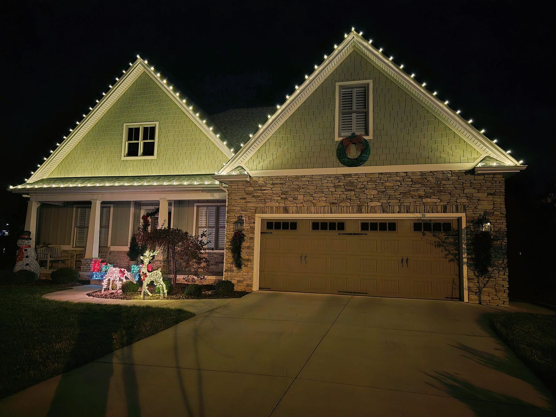 A house at night with Christmas lights outlining the roof, porch, and windows.