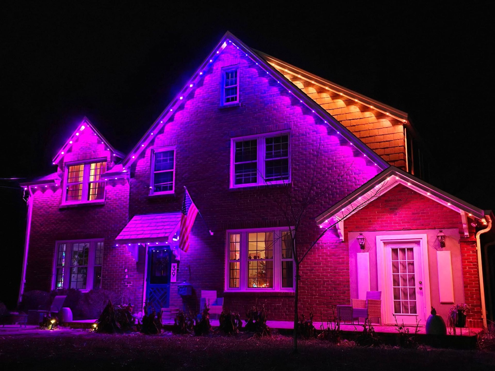 A brick house illuminated with purple and pink lights at night.