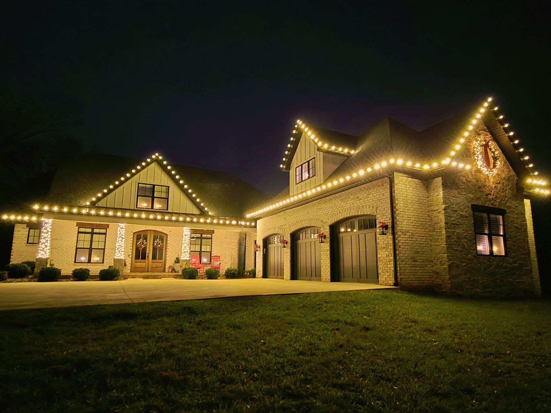A house at night, illuminated by warm white Christmas lights.