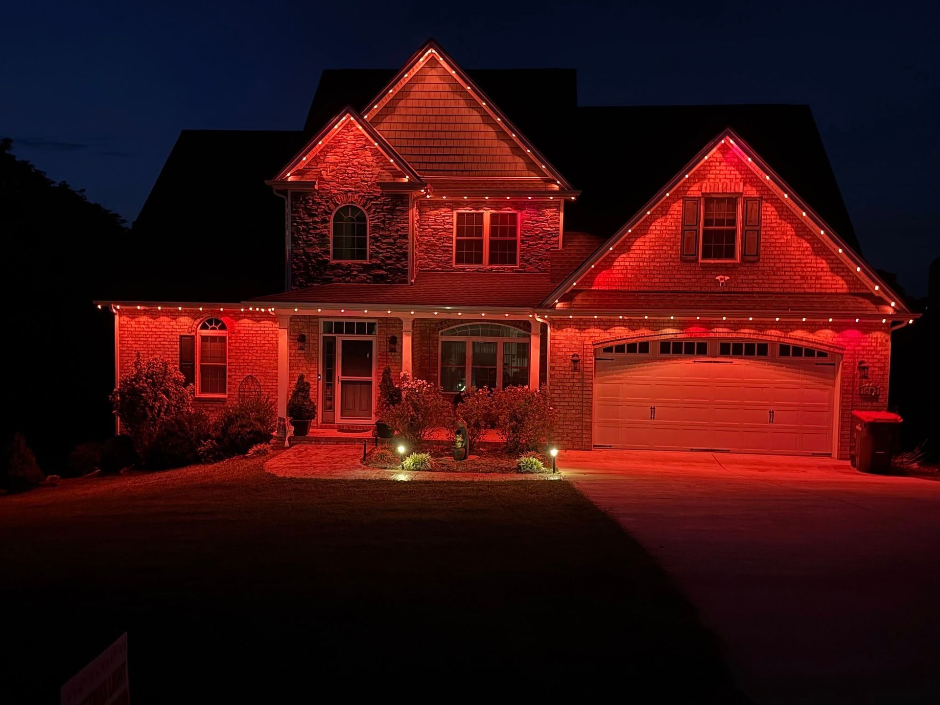 House at night, illuminated in red by string lights, with red ground lighting.