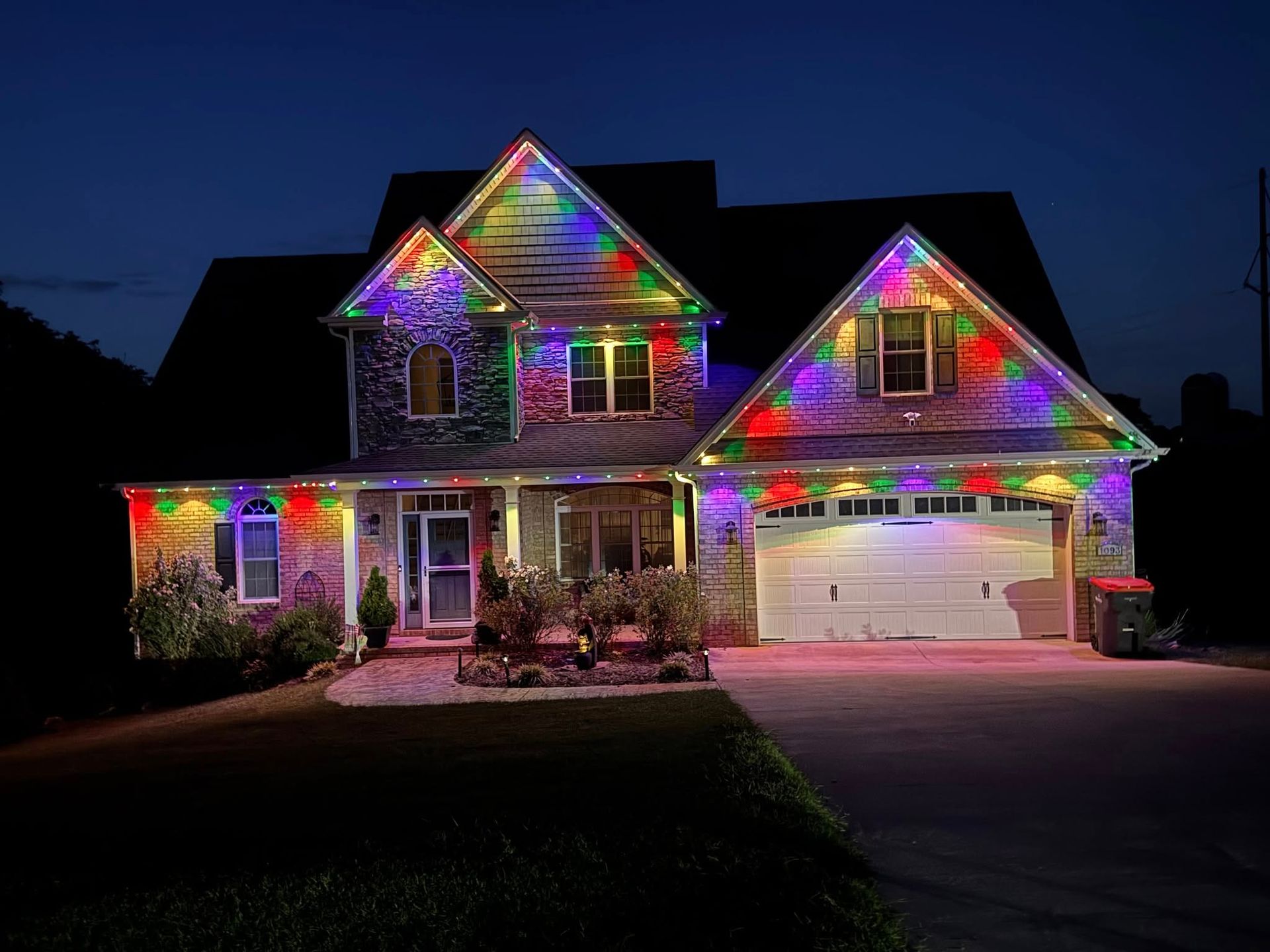 House at night, illuminated with colorful Christmas lights: red, blue, green, and yellow on roof, window