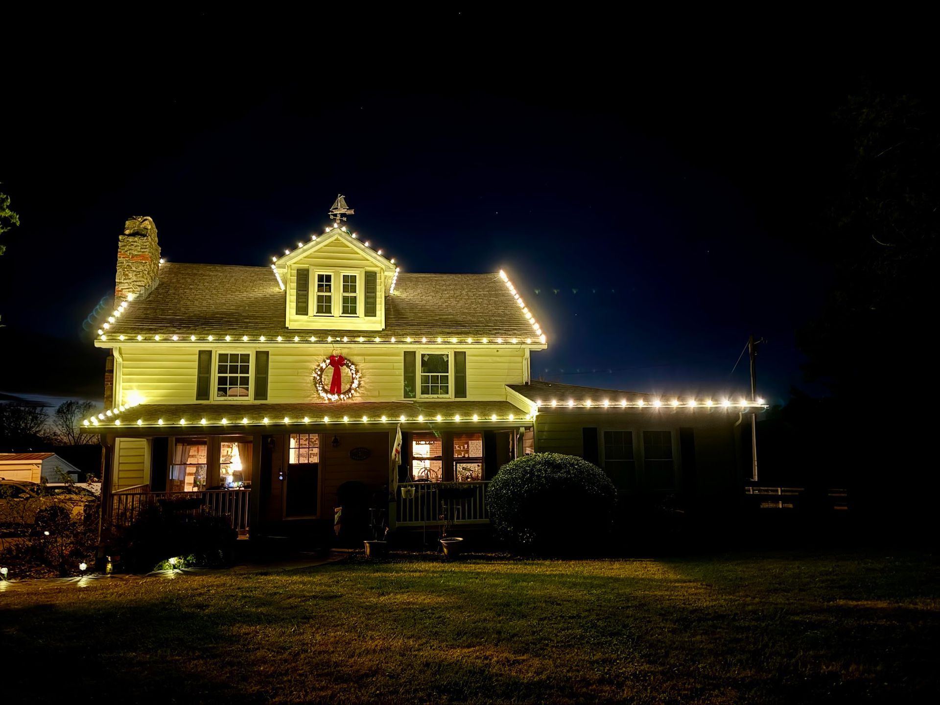 House at night, illuminated with white Christmas lights. 