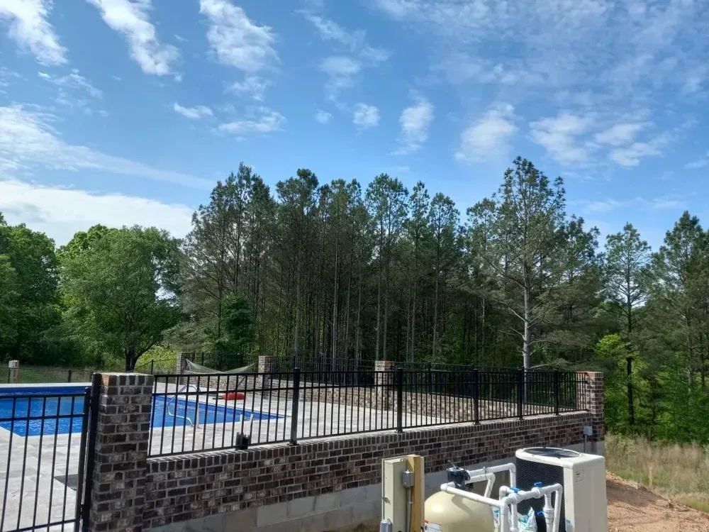 A pool with a fence around it and trees in the background