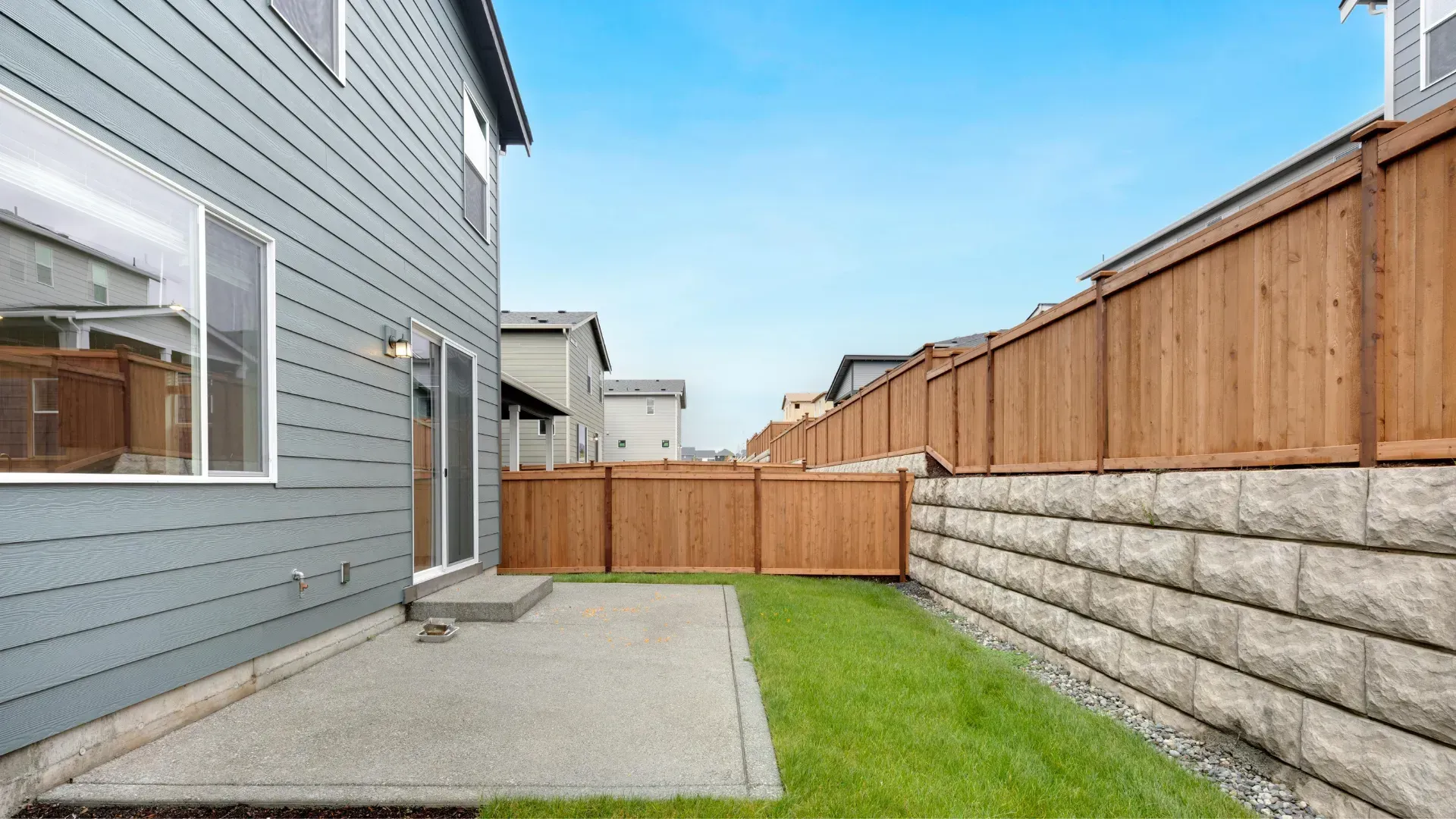 The backyard of a house with a wooden fence and a patio.