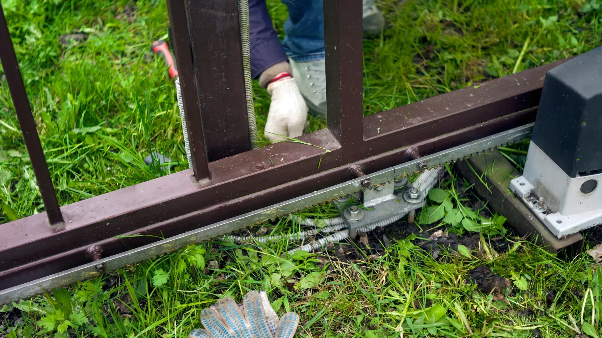 A person is working on a sliding gate in the grass.
