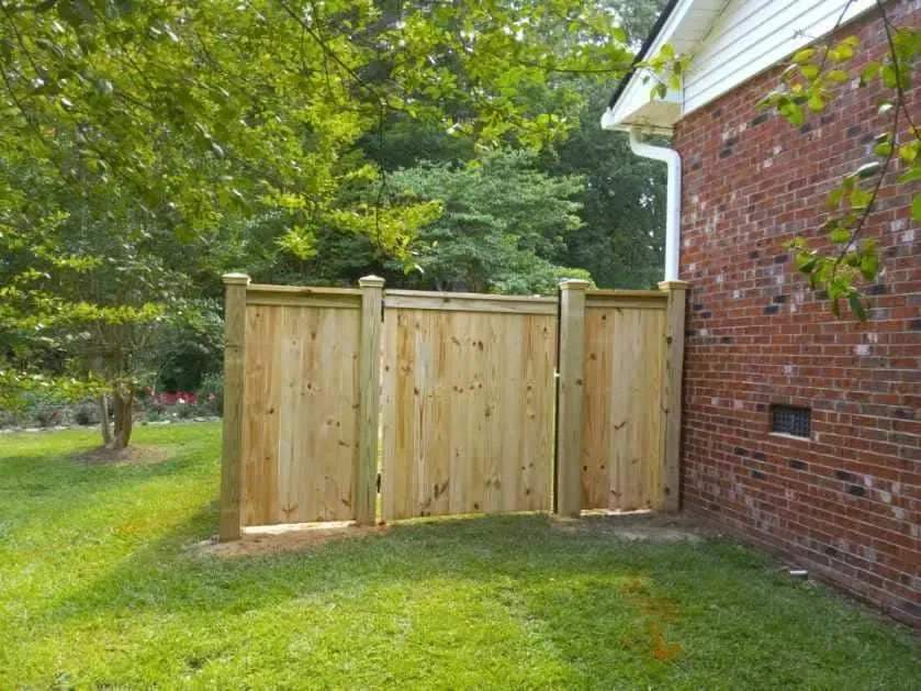 A wooden fence is sitting next to a brick building.