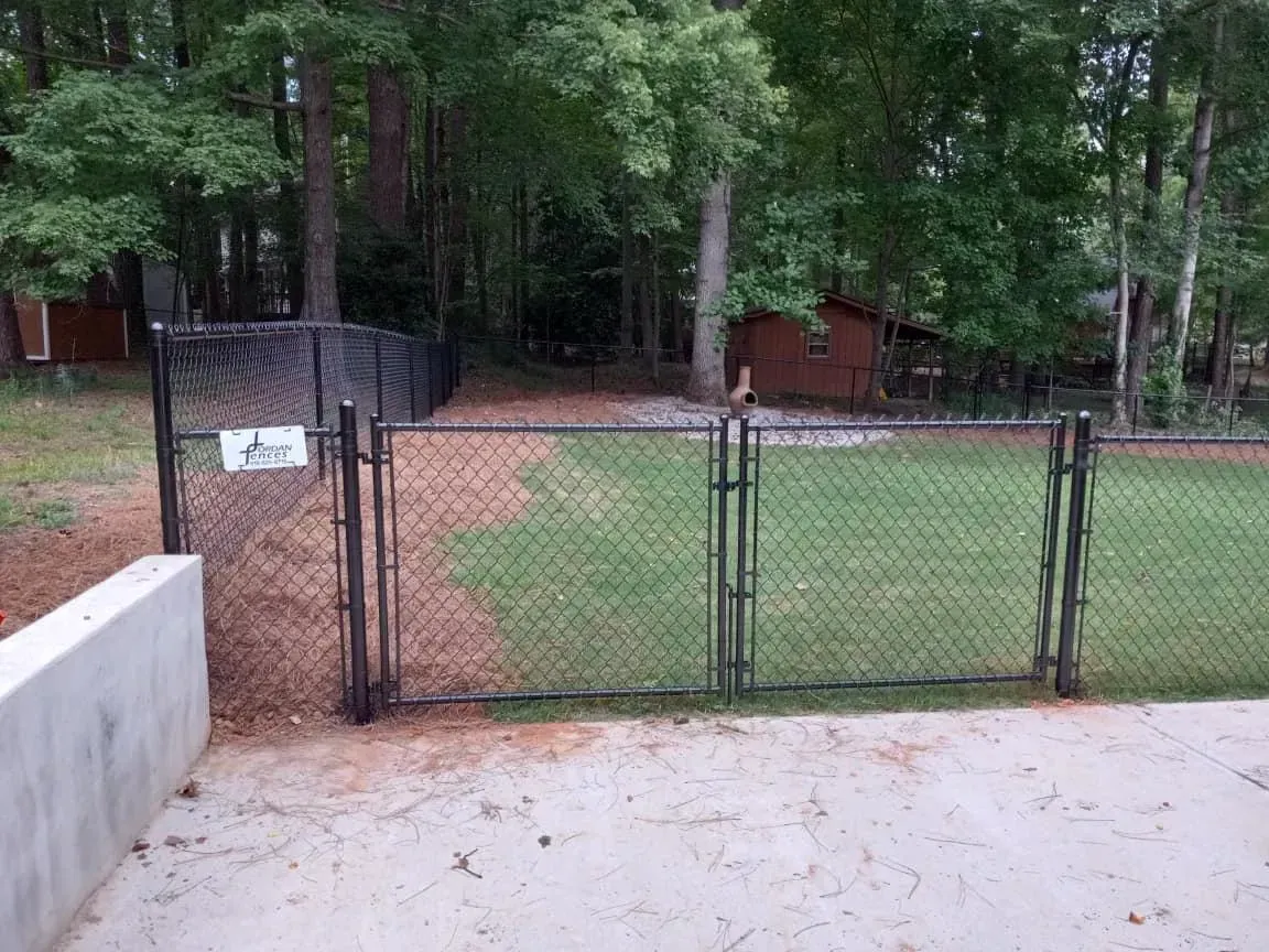 A chain link fence is surrounding a lush green field.
