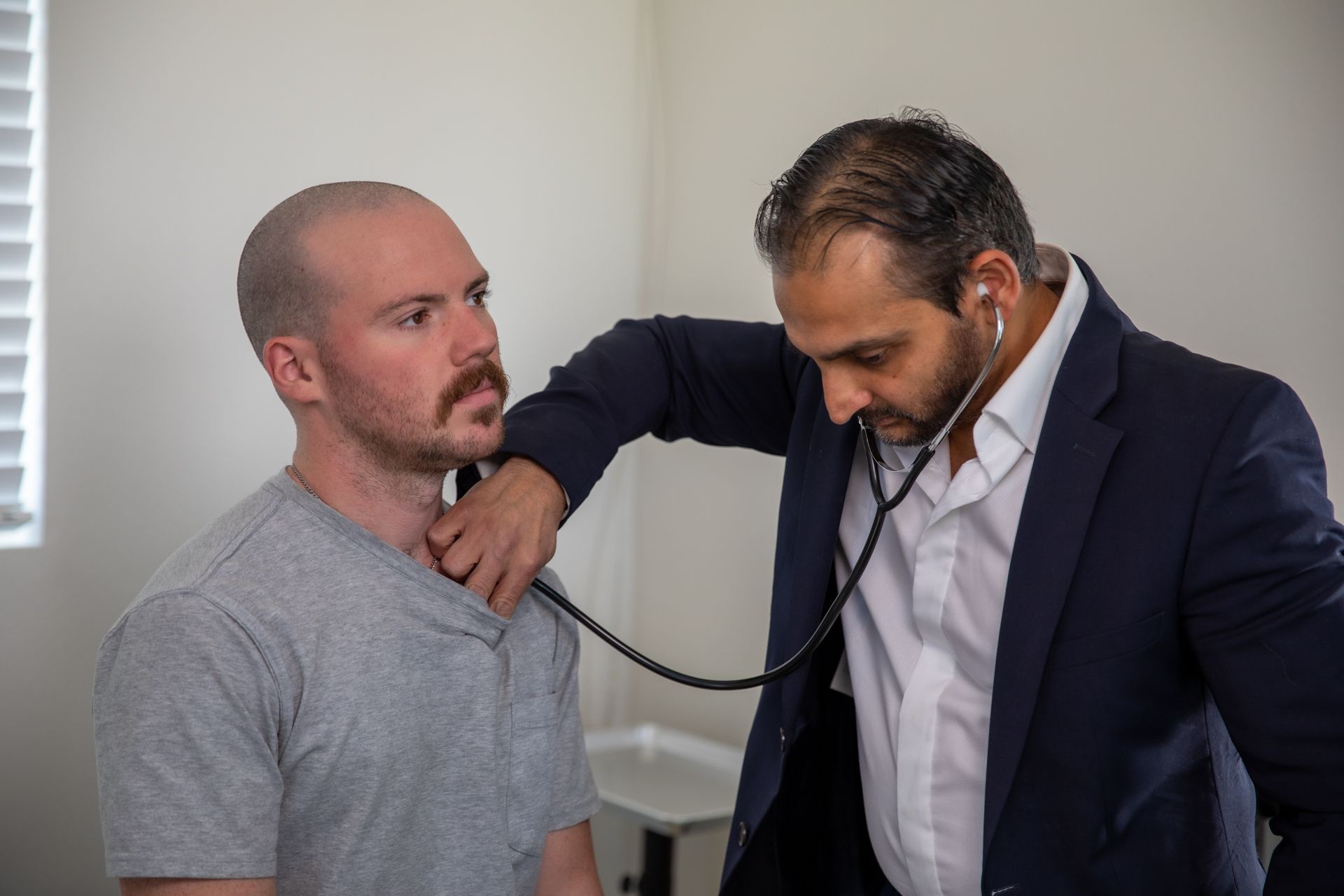 A man is being examined by a doctor with a stethoscope.