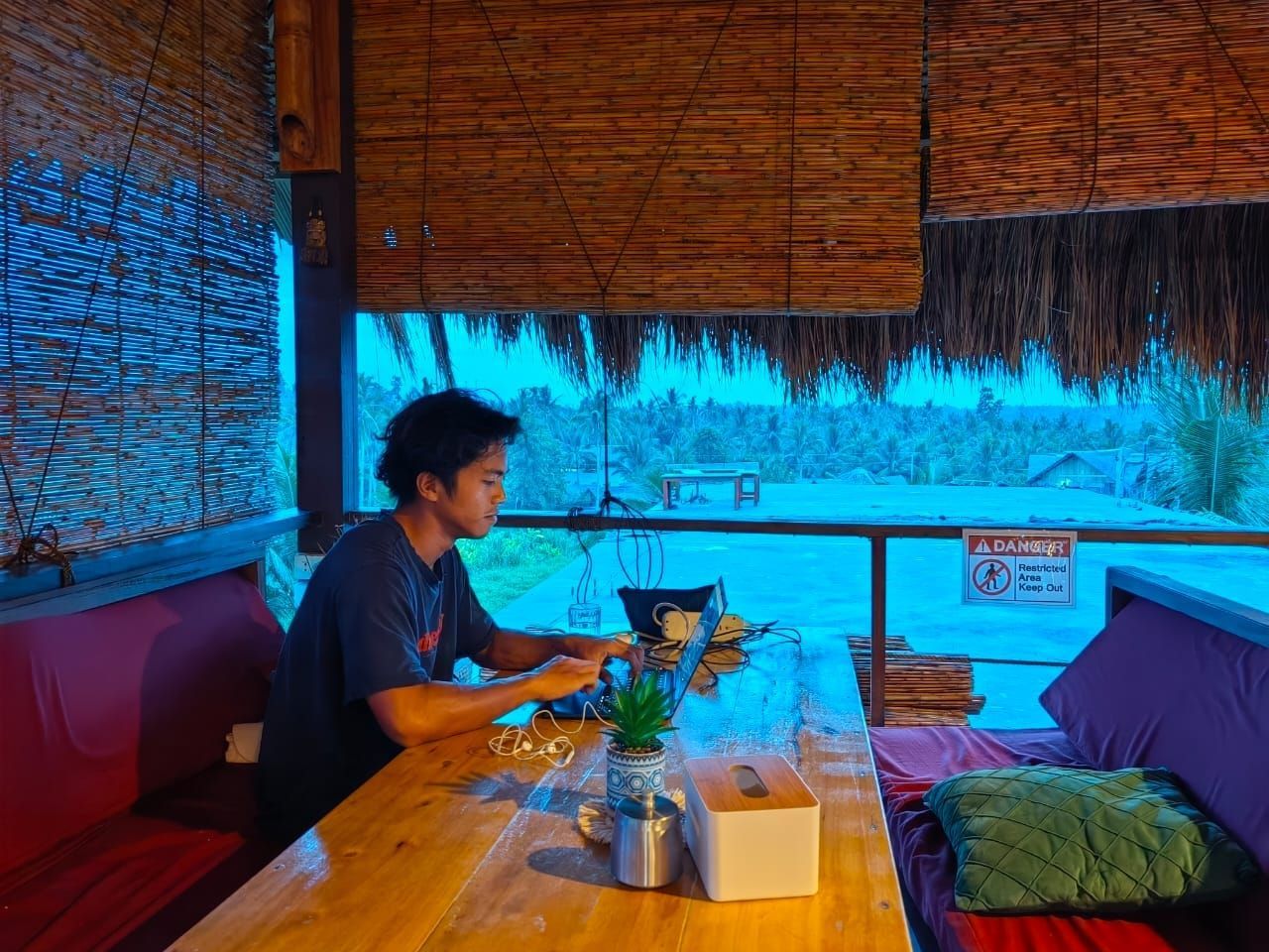 A man is sitting at a table using a laptop computer.