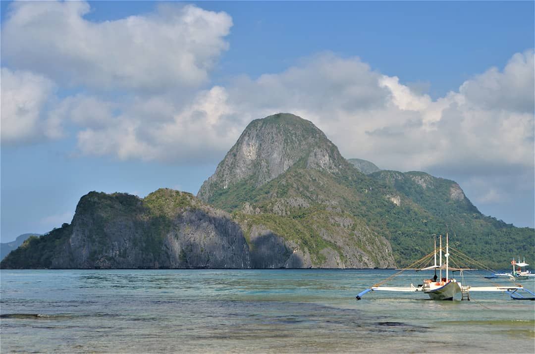 A boat is docked in the water with a mountain in the background.