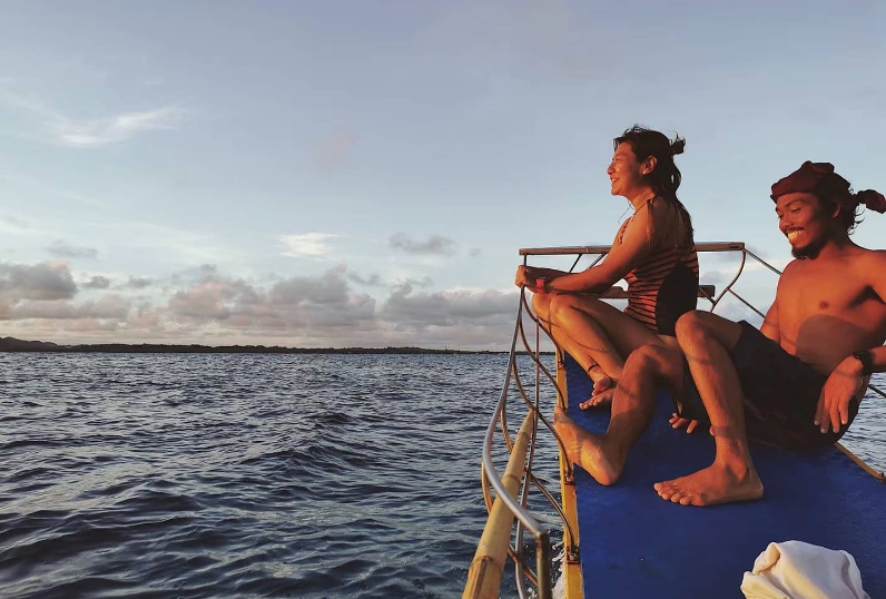 A man and a woman are sitting on a boat in the ocean