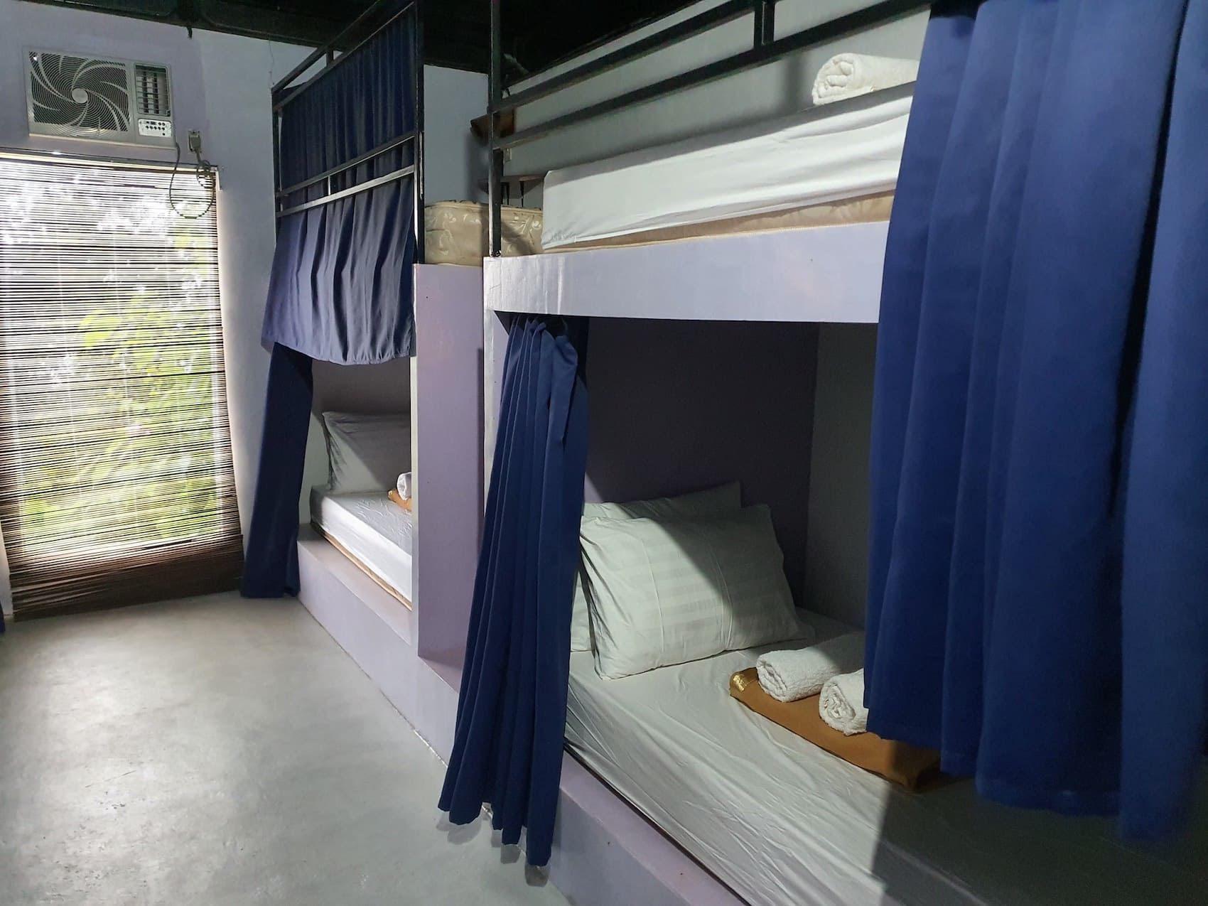 A row of bunk beds with blue curtains in a room.