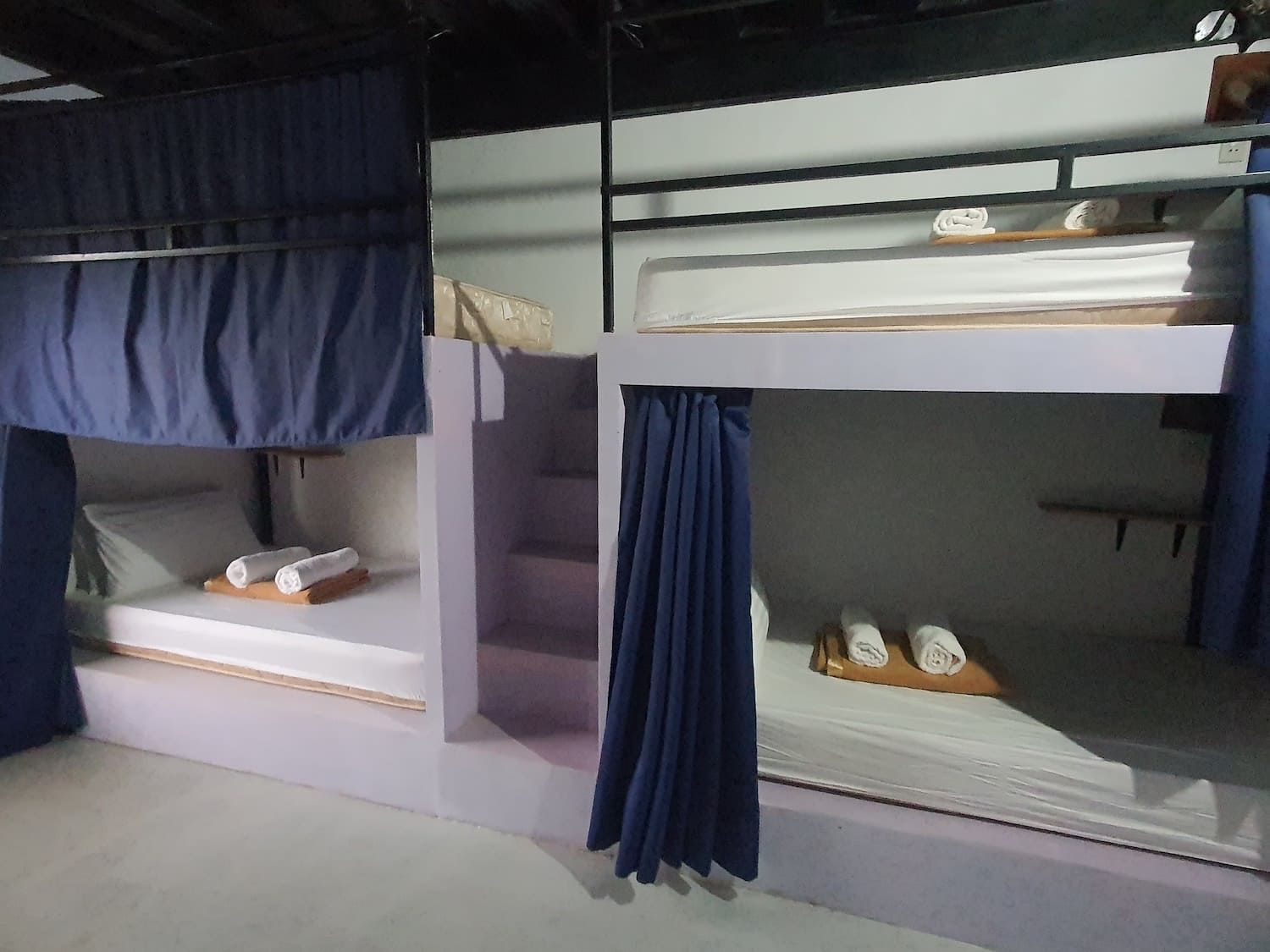 A bunk bed with blue curtains and stairs in a room.