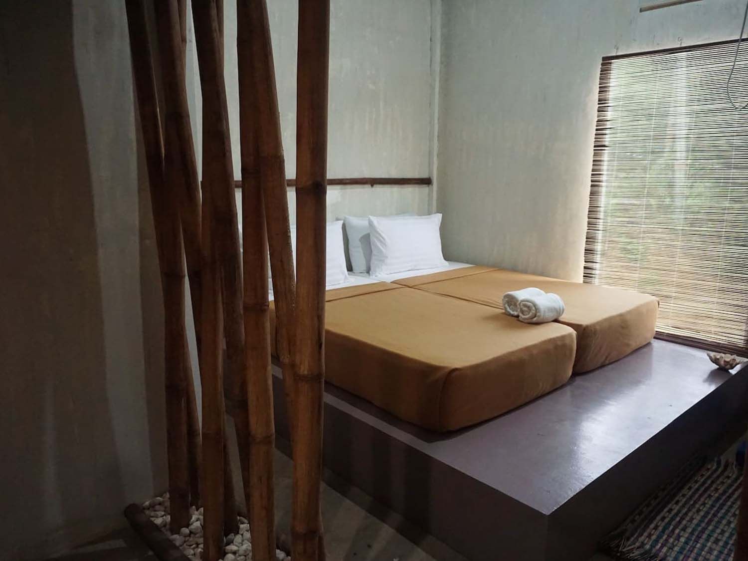 A bedroom with a bed and a window with blinds.