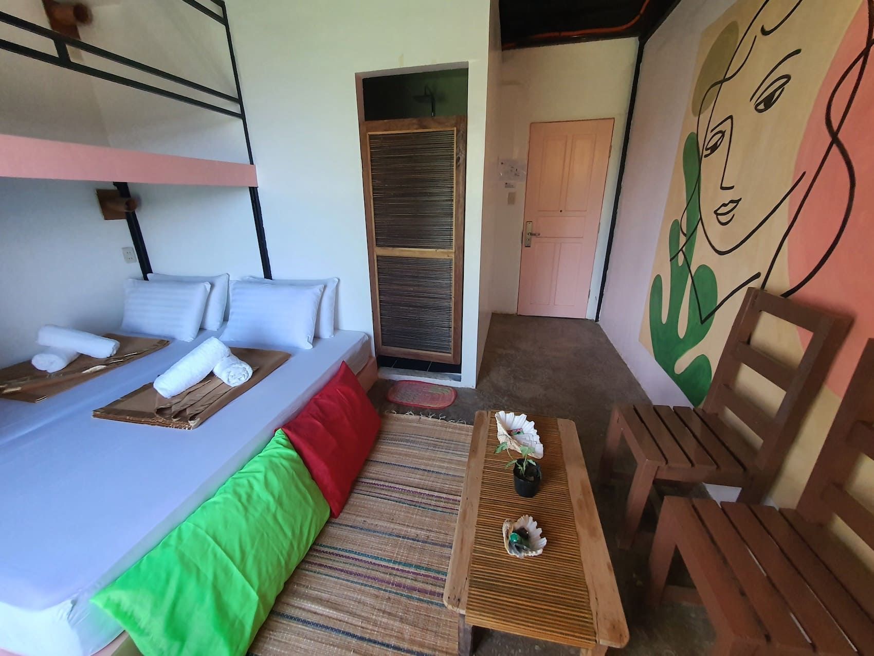 A bedroom with bunk beds , a table , chairs and a painting on the wall.