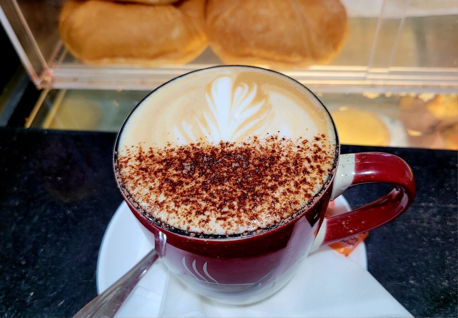 A cup of cappuccino on a saucer with a spoon