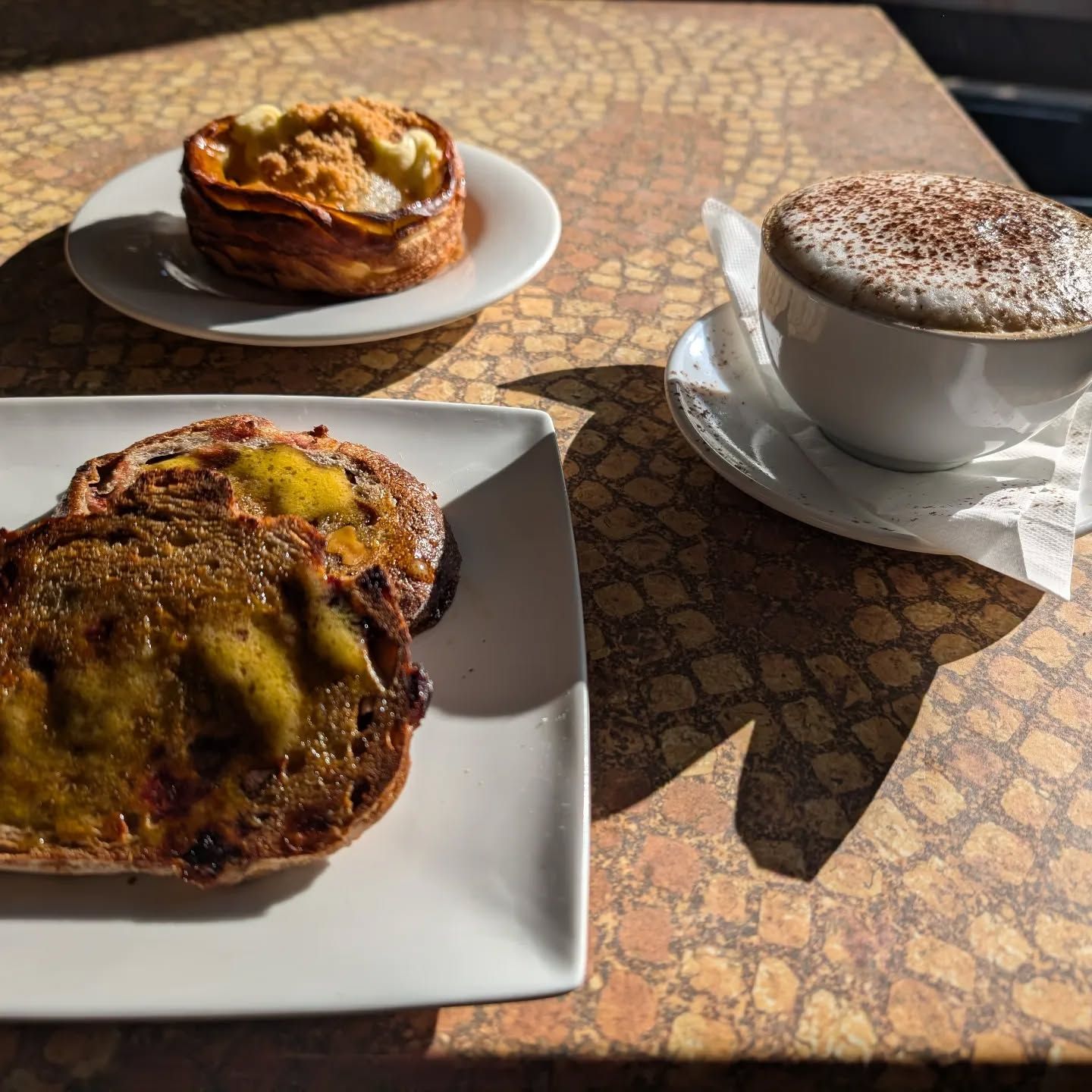 Three plates of food and a cup of coffee on a table