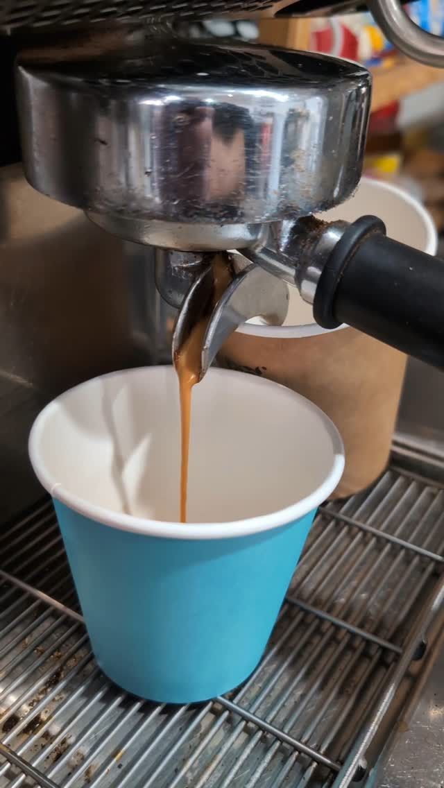 A cup of coffee is being poured into a coffee machine.