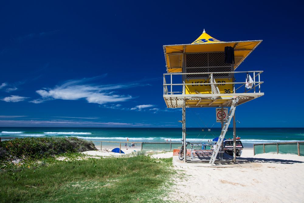 A Yellow Lifeguard Tower on A Beach Next to The Ocean — Creative Commercial Furniture in Surfers Paradise, QLD