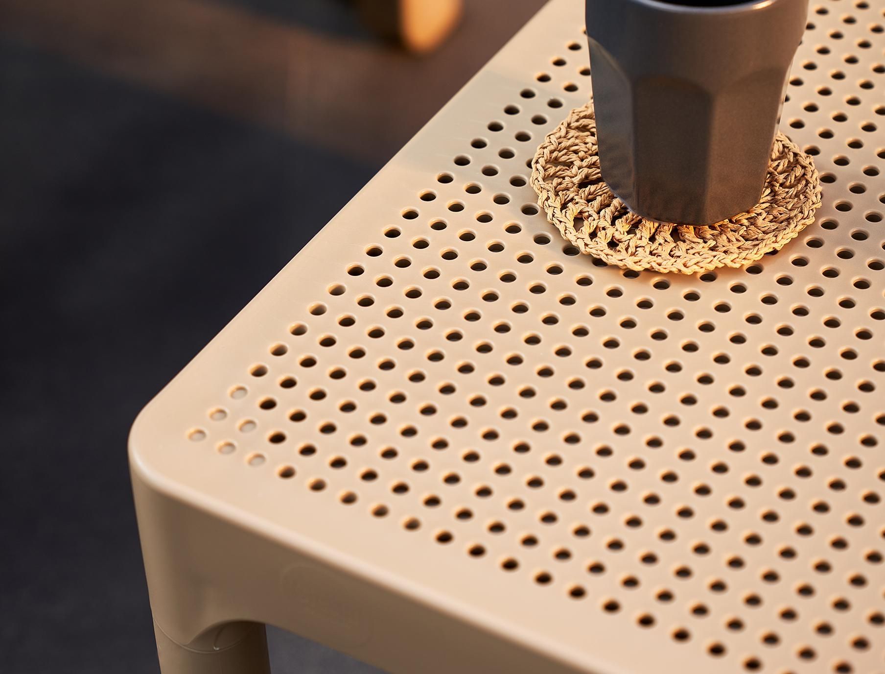 A Cup of Coffee Is Sitting on A Crocheted Coaster on A Table — Creative Commercial Furniture in Cairns City, QLD