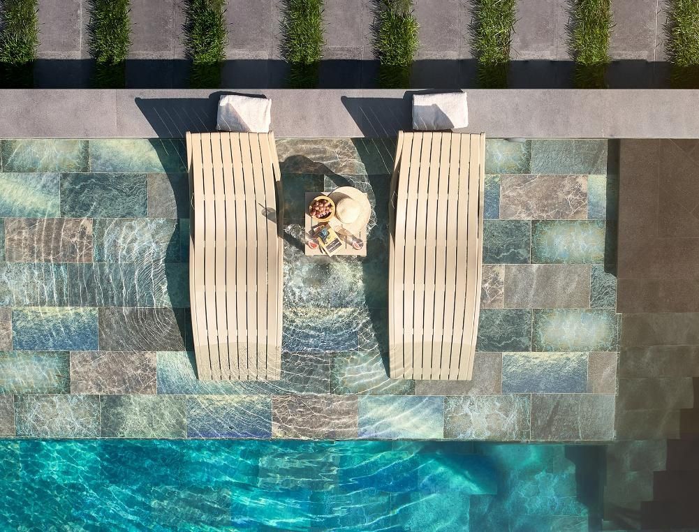 An Aerial View of A Person Sitting on A Lounge Chair Next to A Swimming Pool — Creative Commercial Furniture in Brisbane, QLD