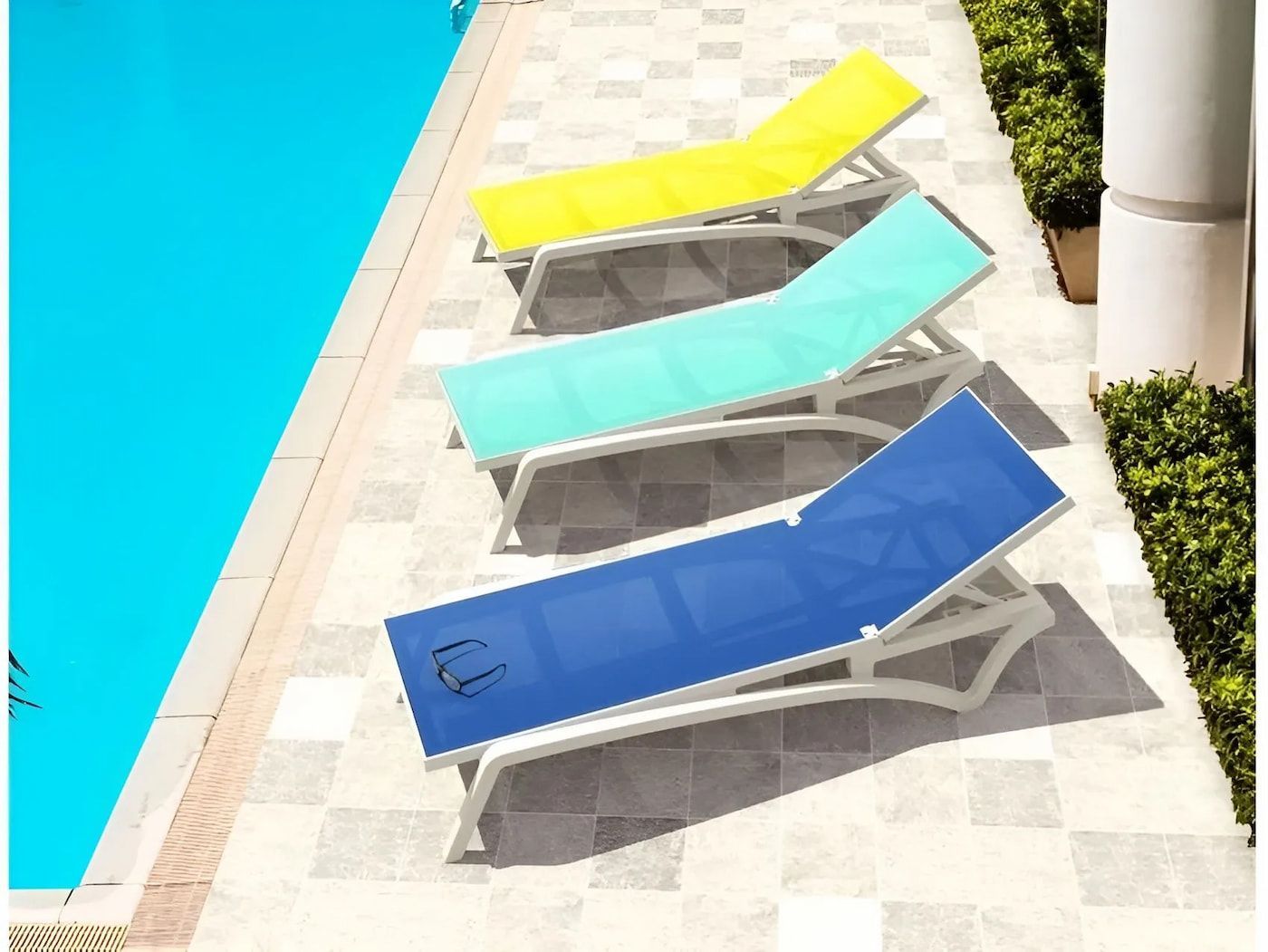 Row Of Colorful Lounge Chairs Next To A Swimming Pool — Creative Commercial Furniture in Cairns City, QLD