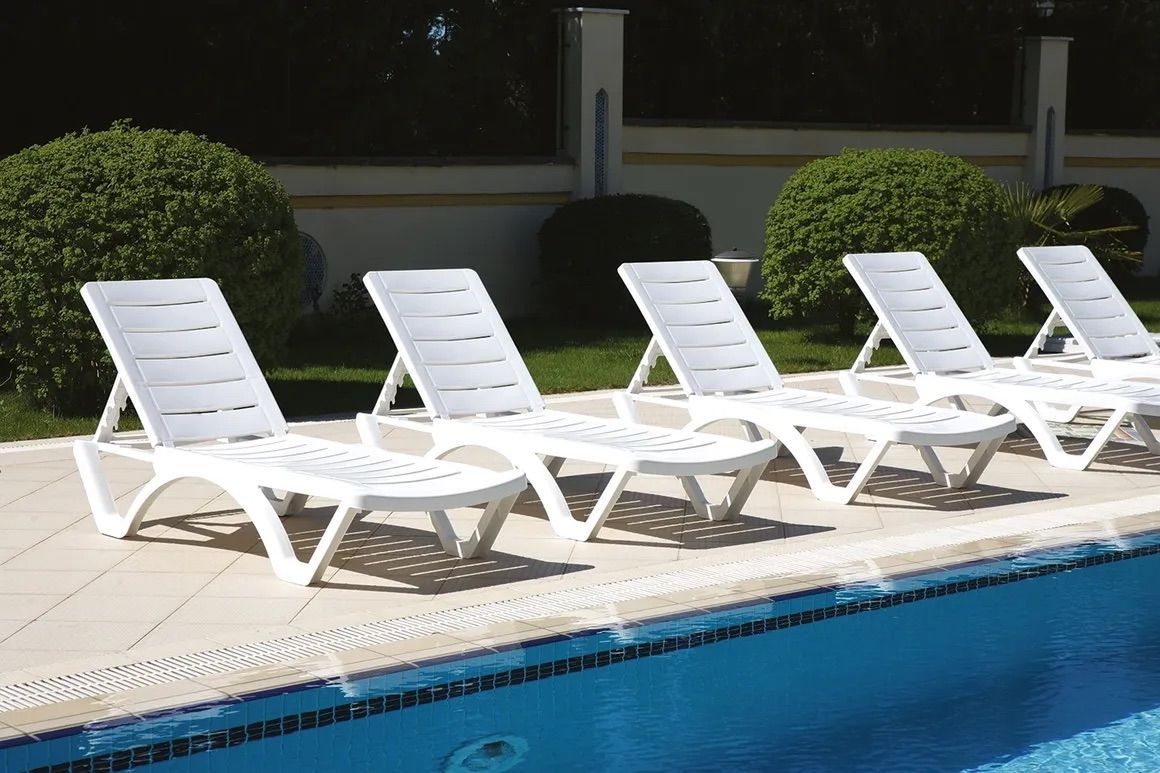 A Row of White Lounge Chairs Sitting Next to a Swimming Pool — Creative Commercial Furniture in Cairns City, QLD 