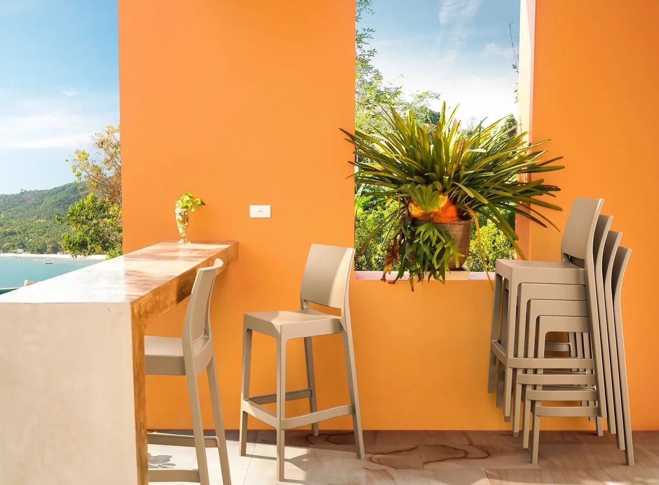 A Stack of Bar Stools Are Sitting Next to a Window on a Balcony — Creative Commercial Furniture in Cairns City, QLD 