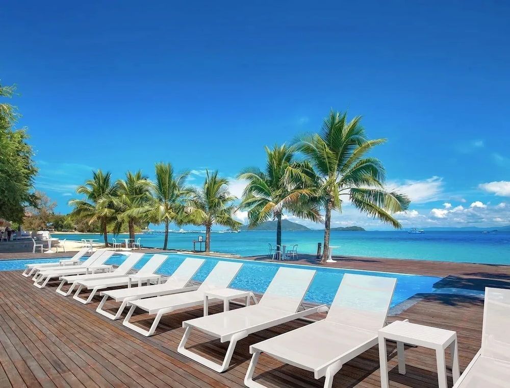 A Row of White Lounge Chairs Are Lined Up Next to a Swimming Pool — Creative Commercial Furniture in Cairns City, QLD 