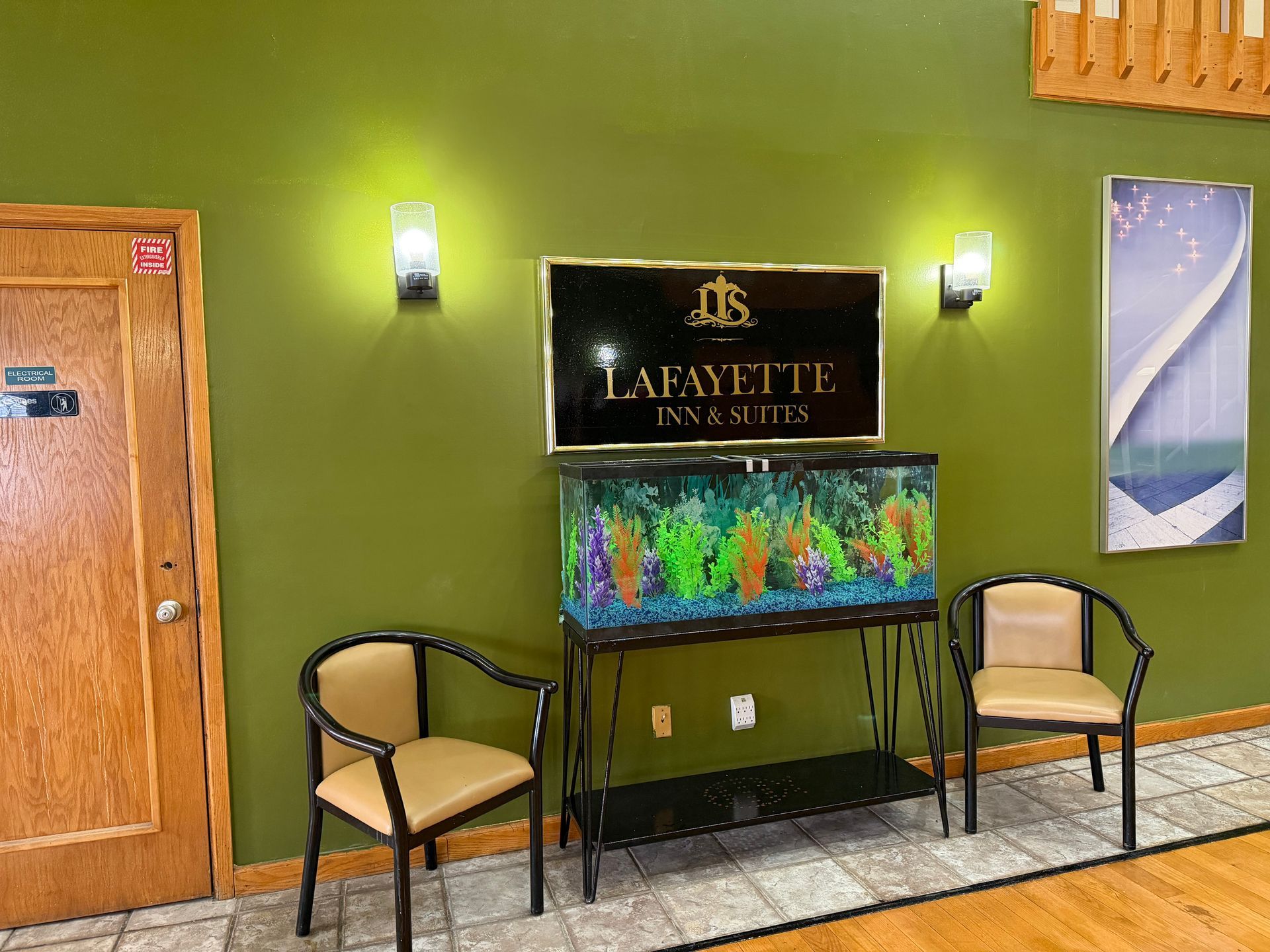 Lobby with a fish tank, law firm sign, chairs, and art on a green wall.