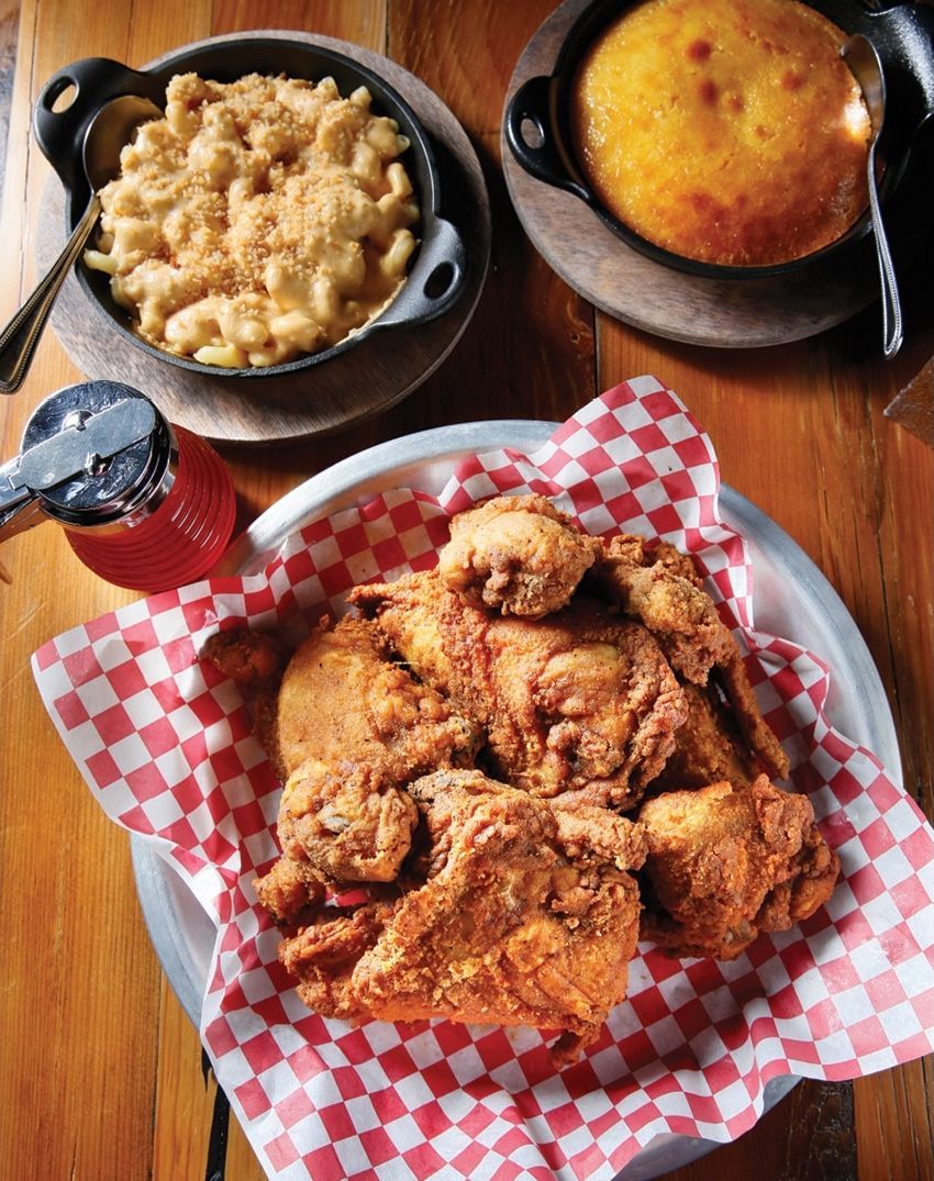 Fried chicken, mac and cheese, and cornbread on a wooden table.