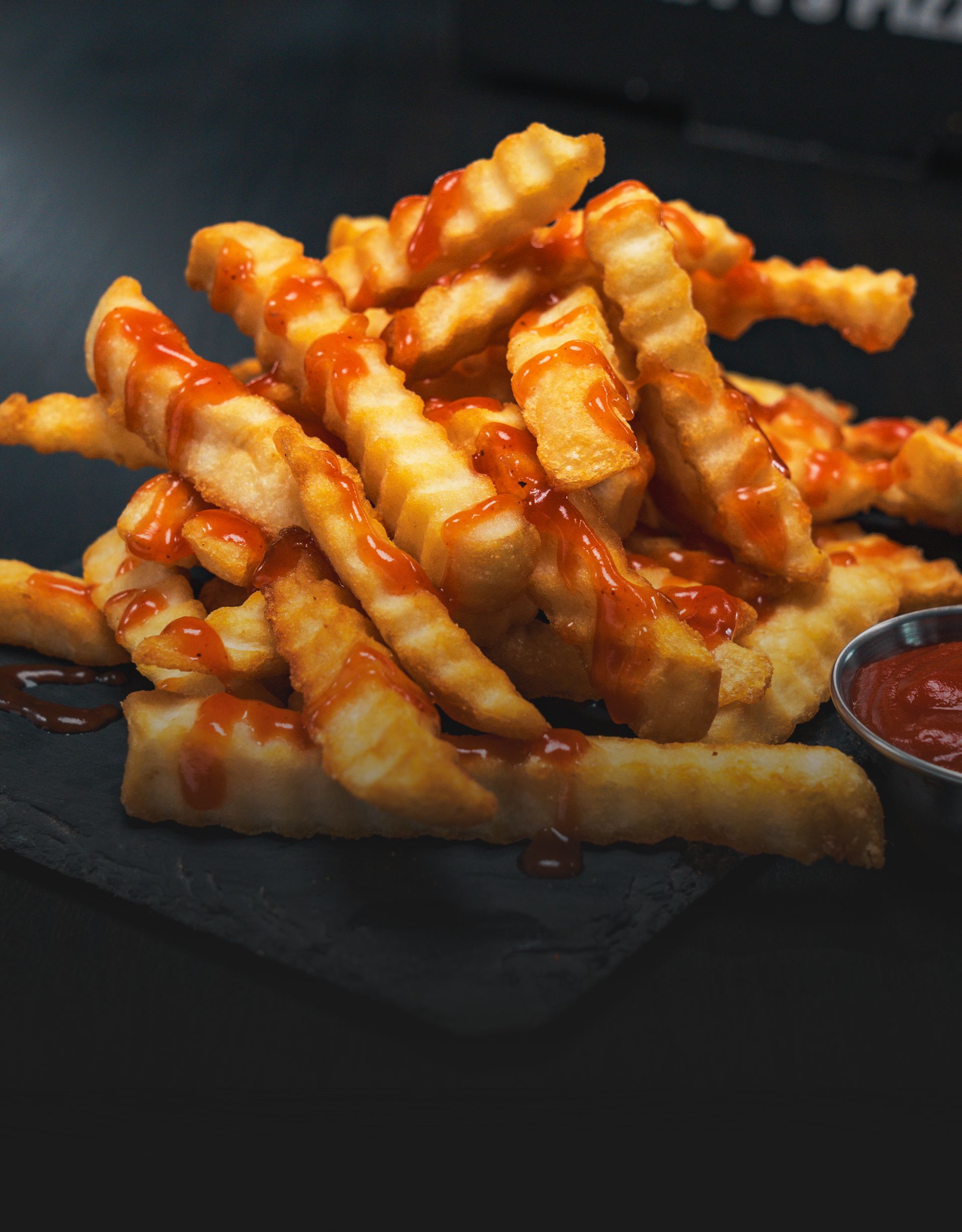 A pile of french fries with ketchup on a table.