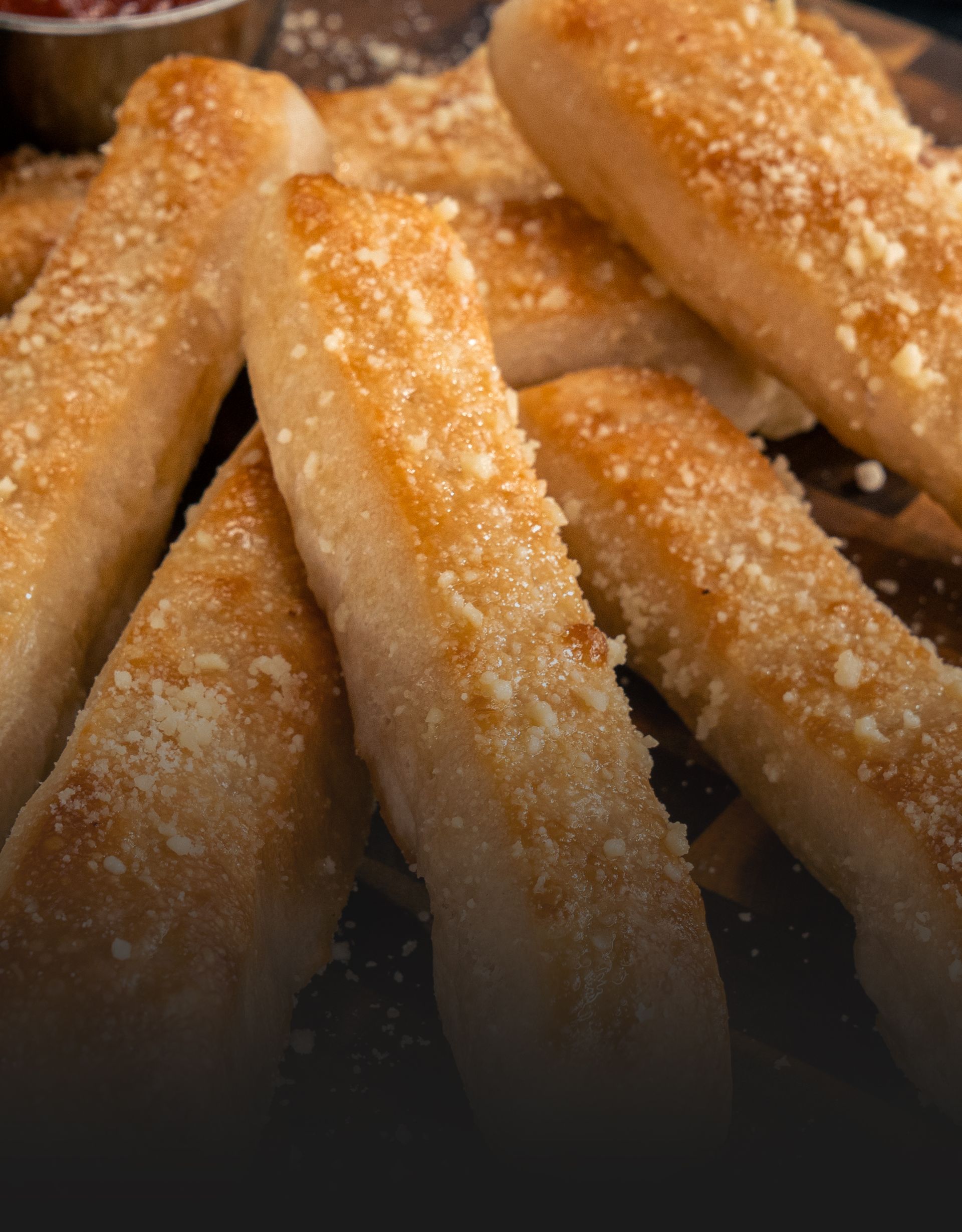 Freshly baked breadsticks, sprinkled with Parmesan and herbs, served golden and warm.