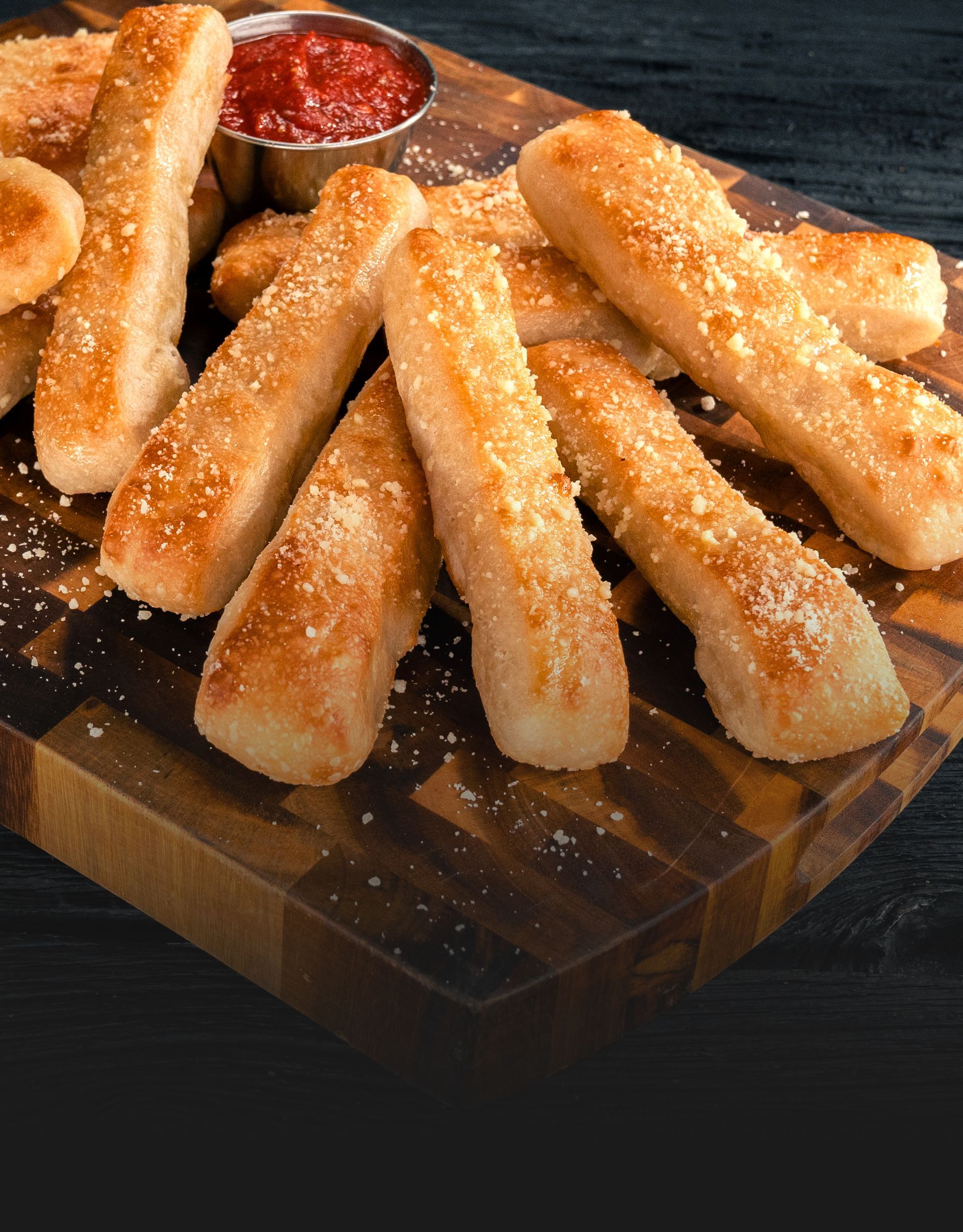 Freshly baked breadsticks sprinkled with Parmesan cheese and garlic seasoning, served warm.