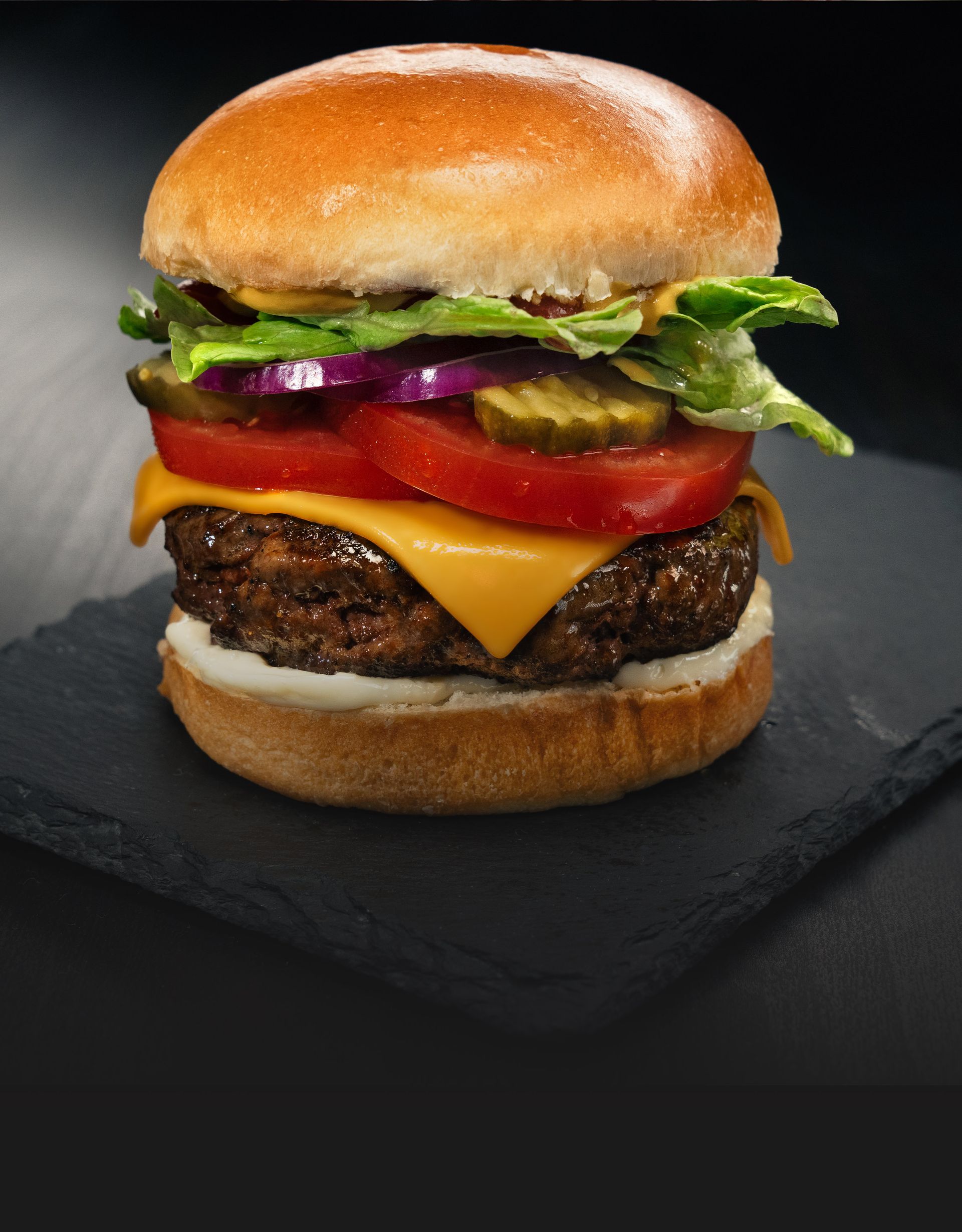 A hamburger with onion rings and french fries on a table.