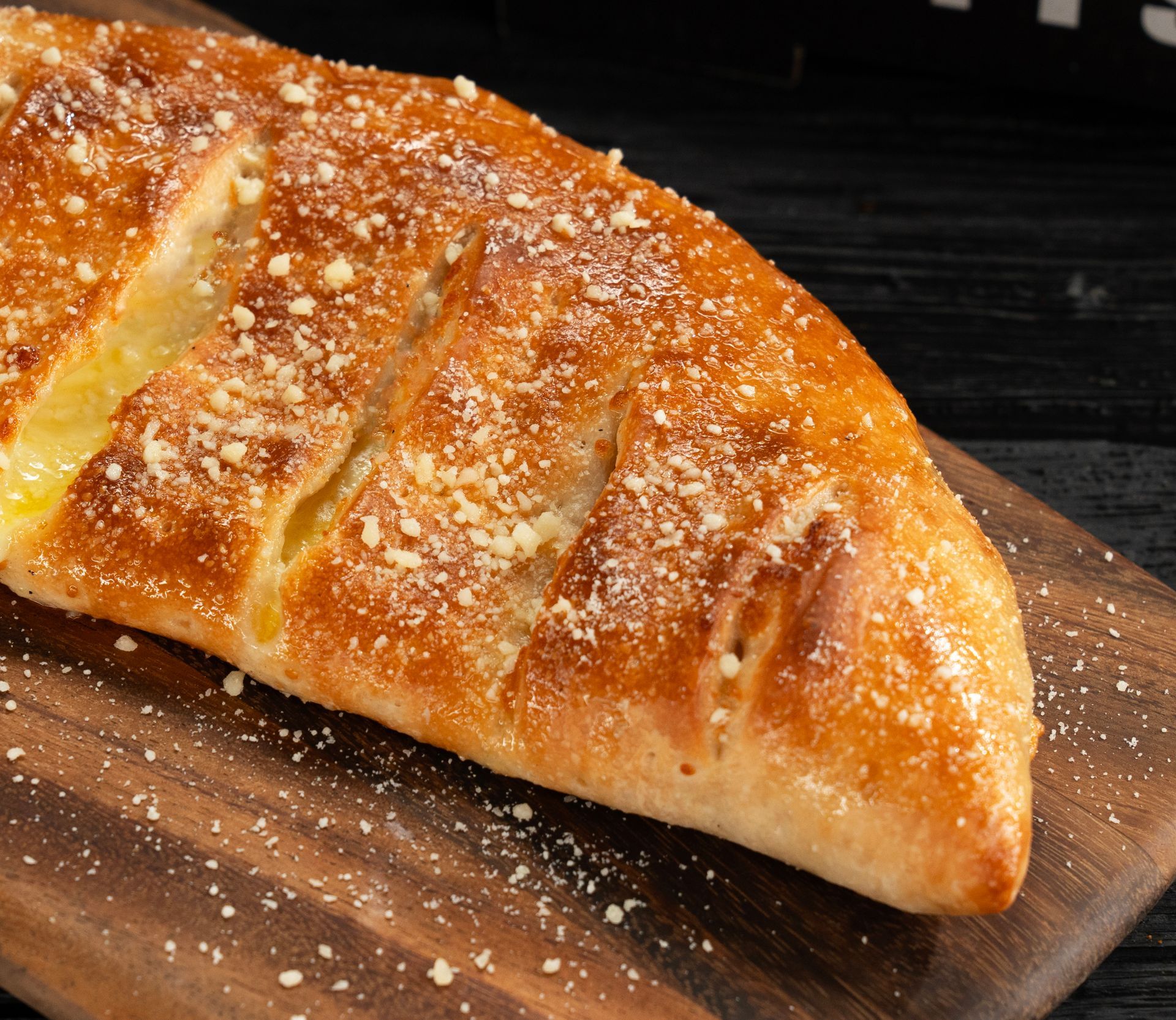 A close up of a pizza calzone on a wooden cutting board.