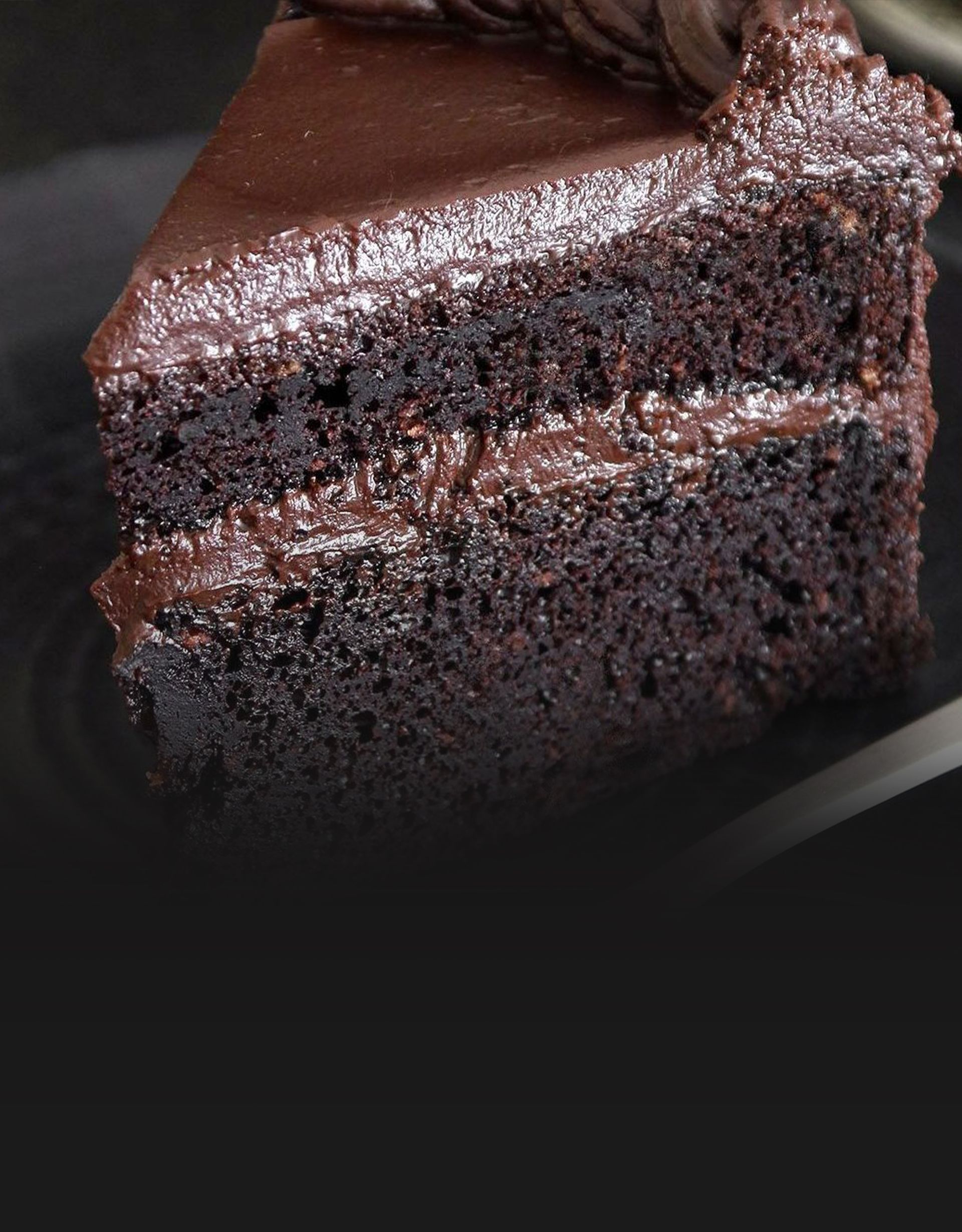 Rich and moist chocolate cake slice, layered with decadent chocolate frosting.