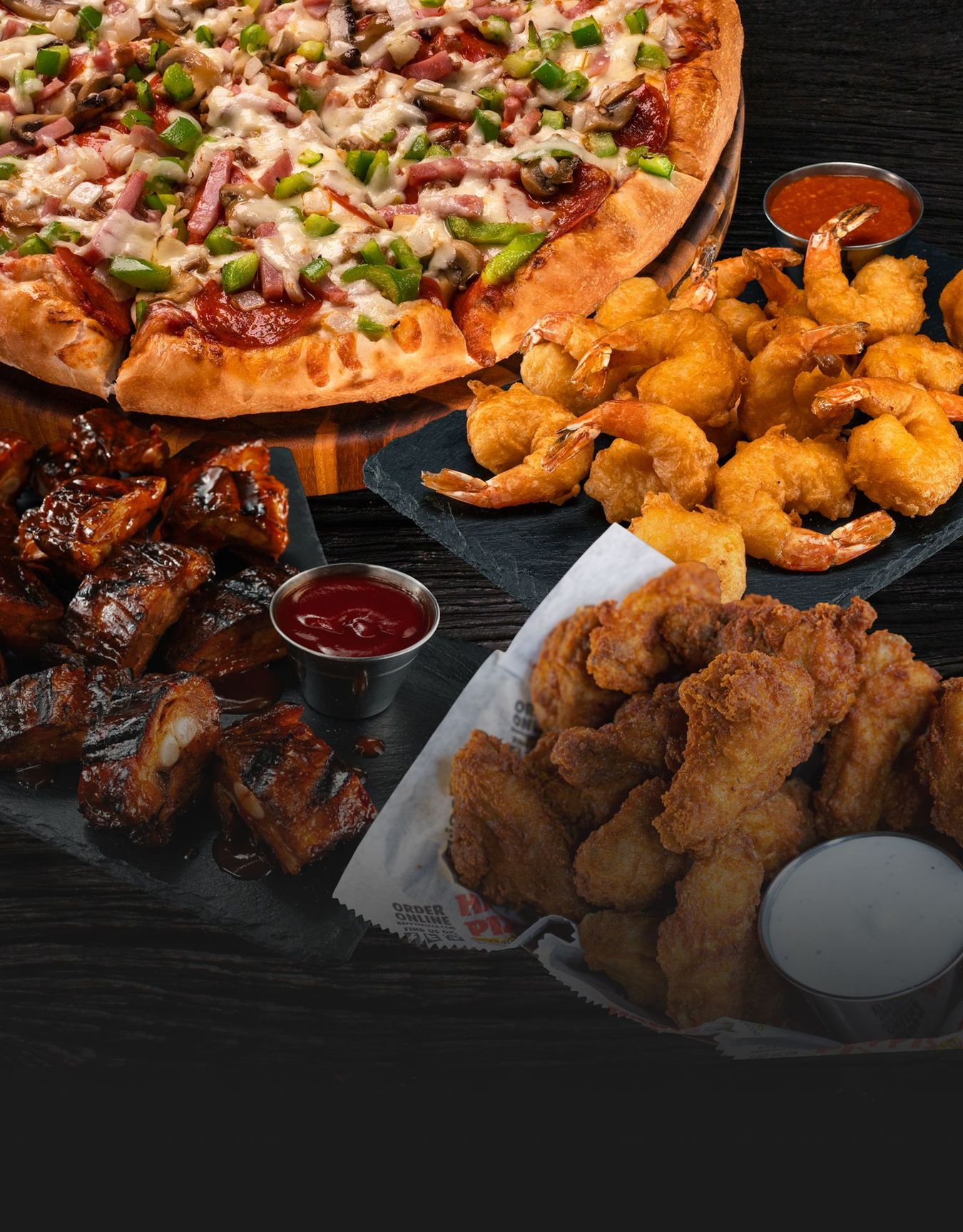 A pizza , shrimp , and chicken wings are on a table.