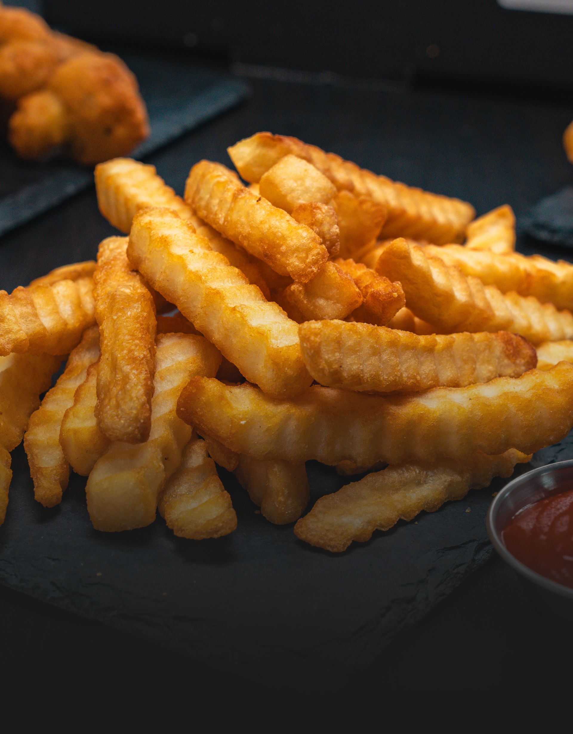A pile of french fries with ketchup on a table.