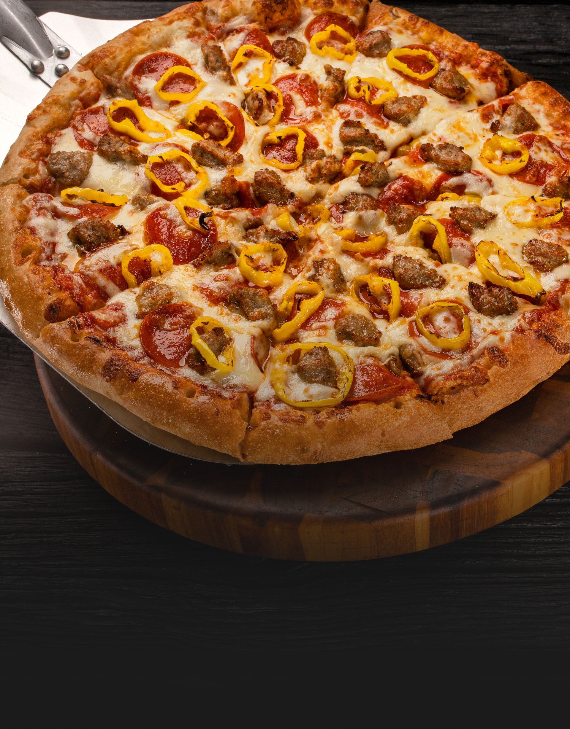 Gourmet pizza topped with sausage, banana peppers, and fresh vegetables on a crispy crust.