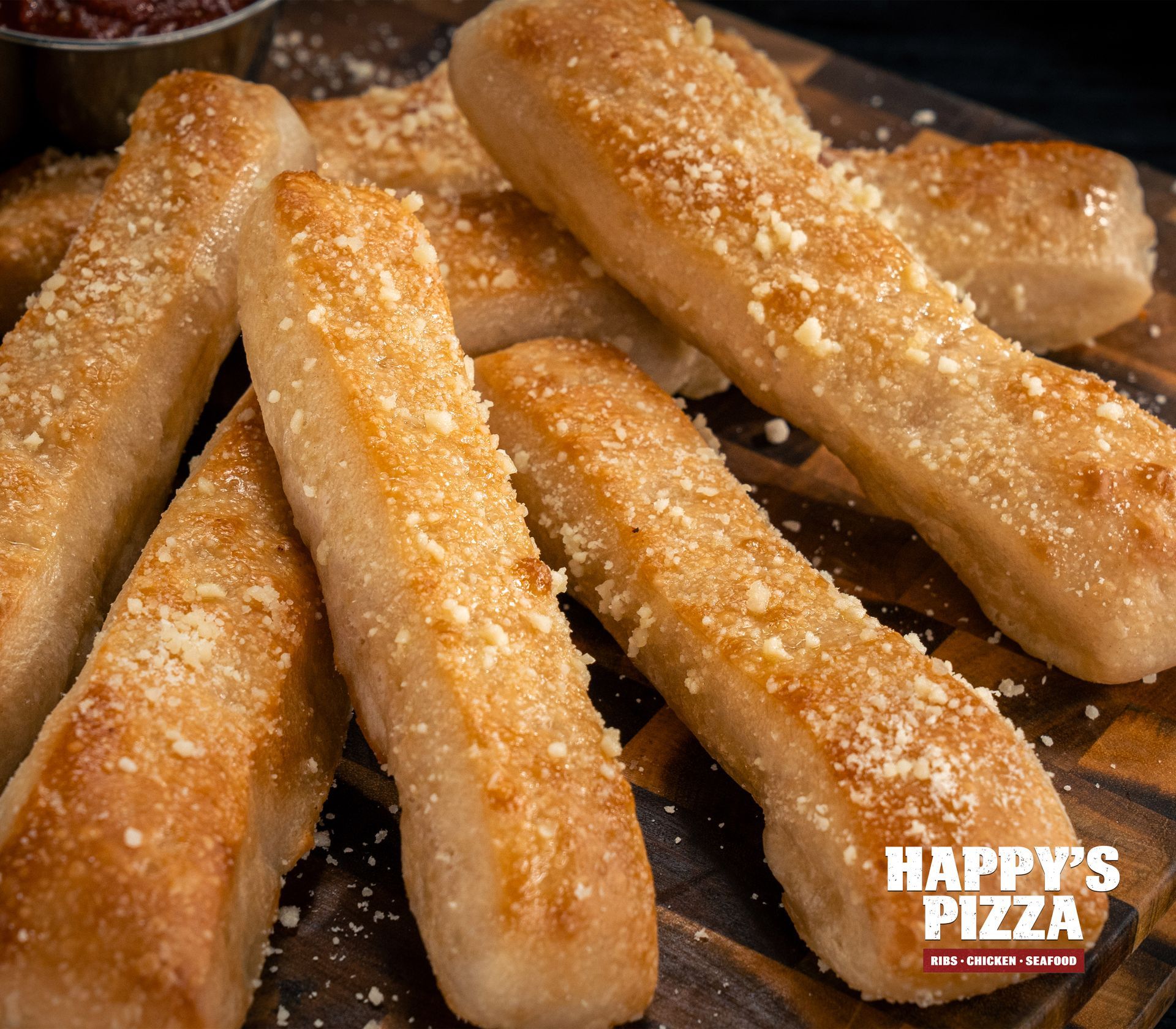 A wooden cutting board topped with garlic bread sticks from happy 's pizza