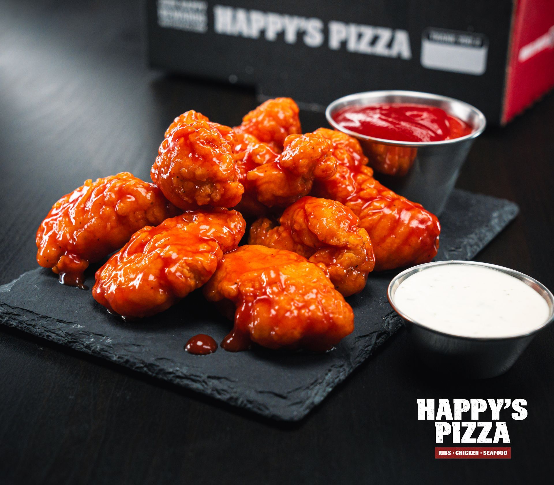 A tray of chicken wings with ketchup and white sauce from happy 's pizza