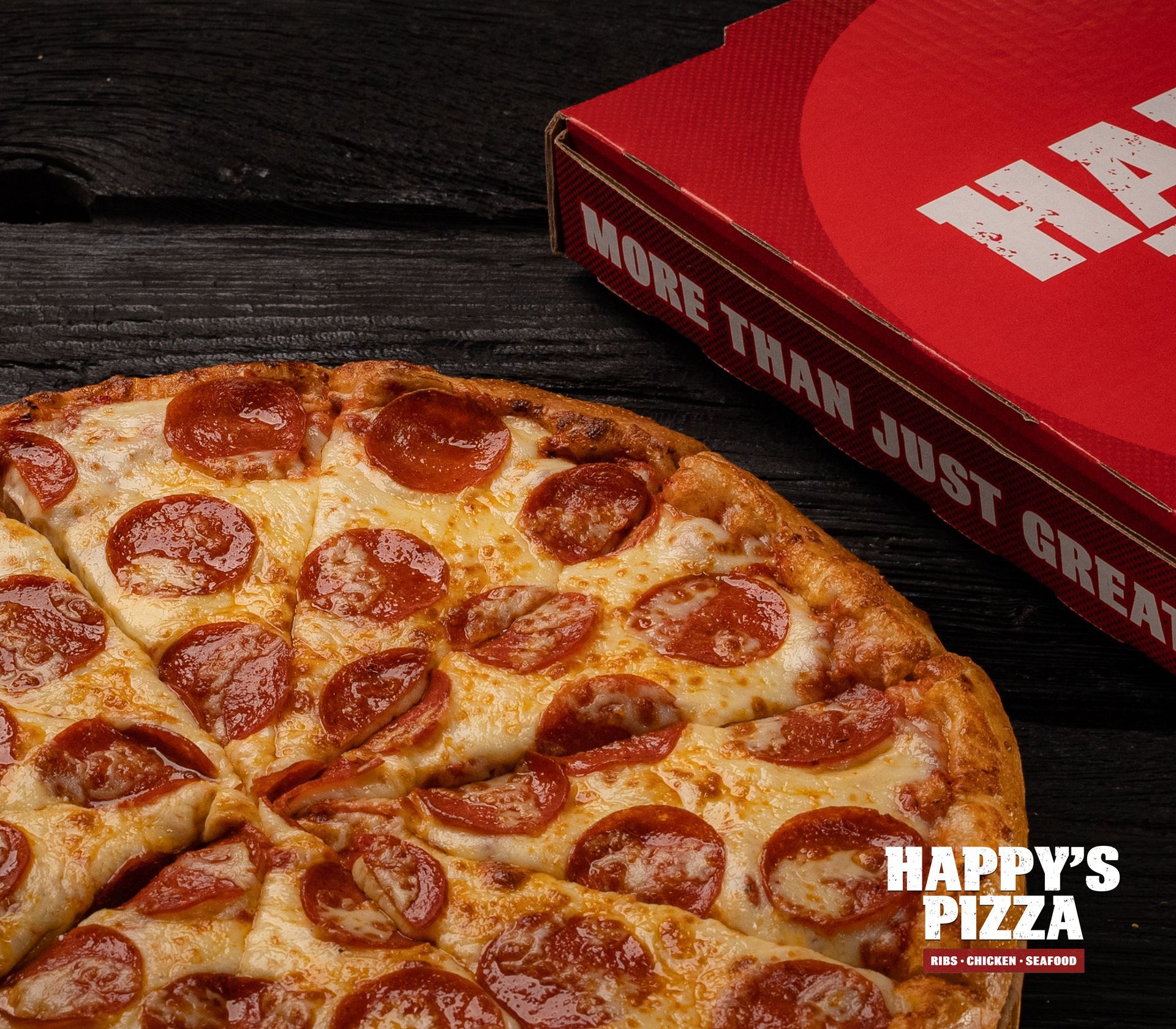 A pepperoni pizza next to a happy 's pizza box